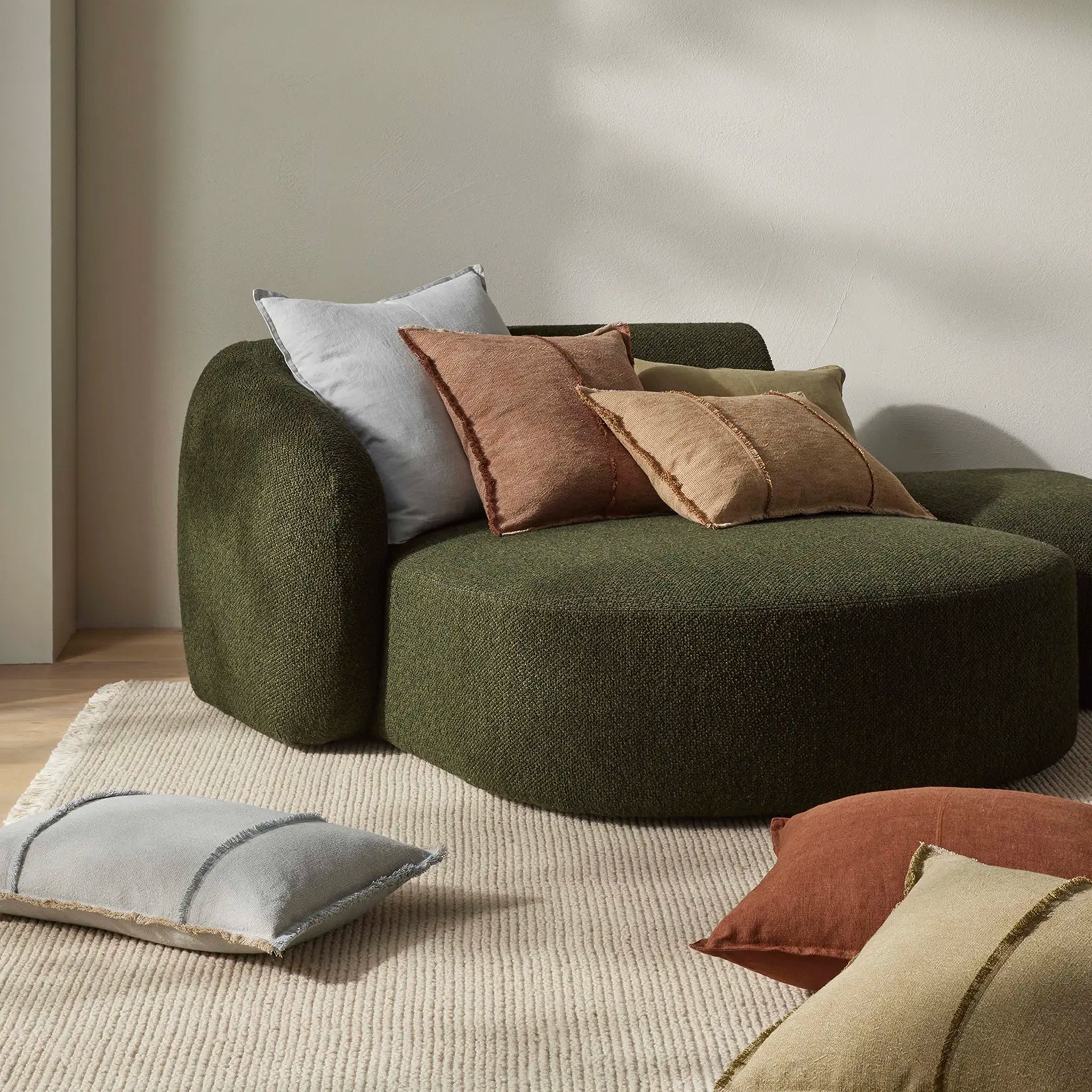 Green sofa with colorful cushions in a room setting