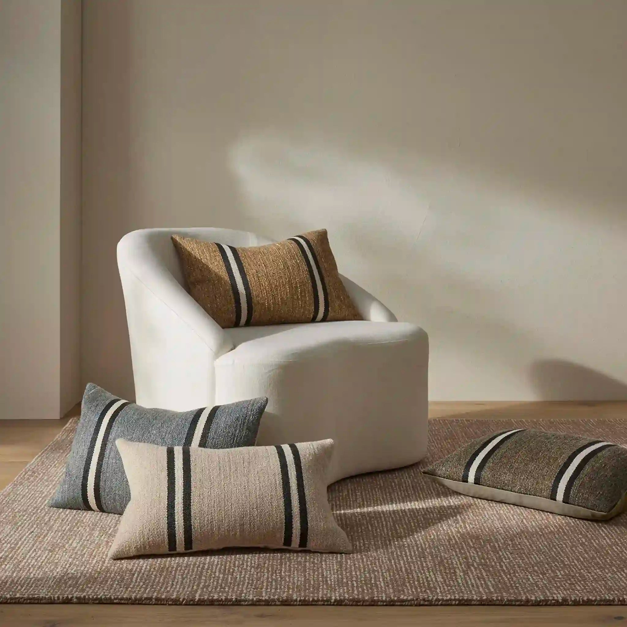 White armchair with striped cushions on a wooden floor and beige wall