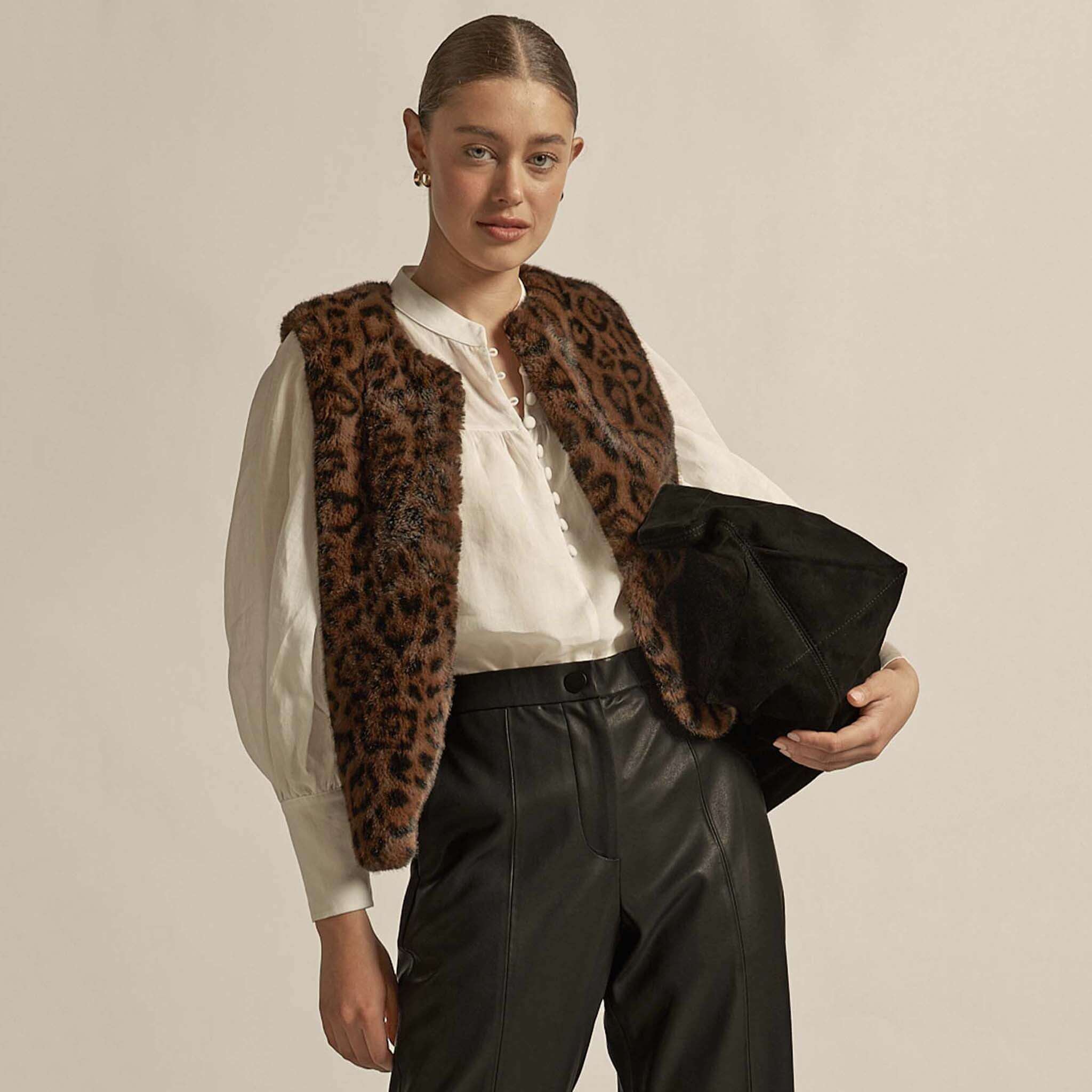 Alt Tag: Zoe Kratzmann Affirm Vest - Ocelot faux fur vest in ocelot print styled over white blouse with black leather pants, cropped layering piece
