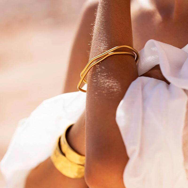 Alt Tag: Kirstin Ash Form Collection Botanica Bangle gold-toned sculptural bangle on wrist, organic windswept design, stackable jewelry