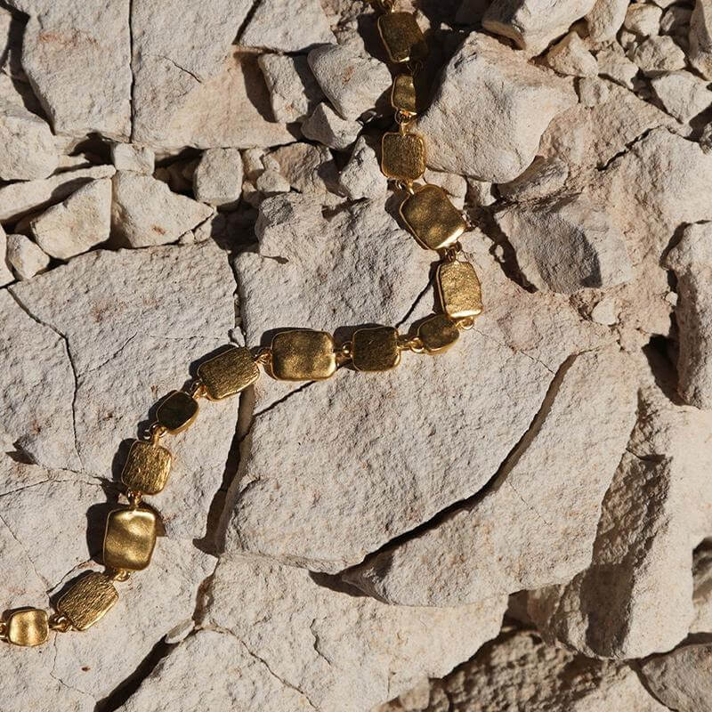 Alt Tag: Kirstin Ash Form Collection Cascade Bracelet gold linked sculptural bracelet with brushed metal texture on natural stone background