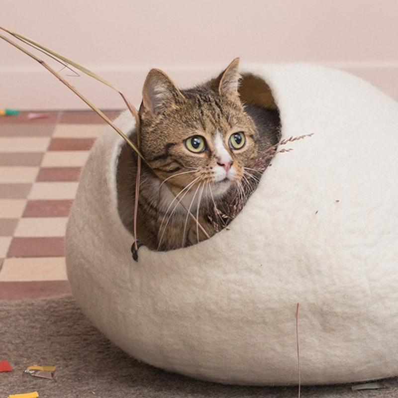 A white-colored felt cat basket with a cat inside, handcrafted and made from 100% felt.