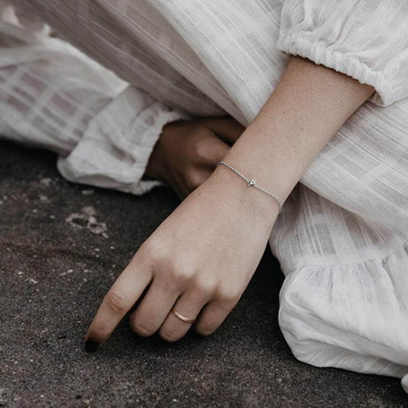 Alt Tag: Sophie Little Letter Bracelet - Sterling Silver on wrist, delicate initial charm on fine chain, everyday layered bracelet