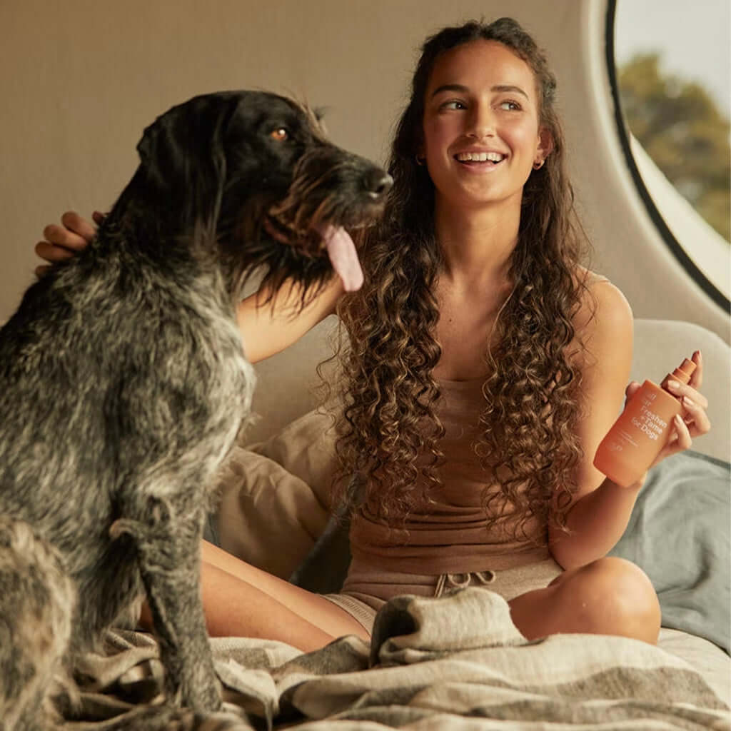 Alt Tag: Woman holding Ashley & Co Ruff Star + Tame for Dogs Freshening Spray with dog on bed, plant-based coat freshener between washes