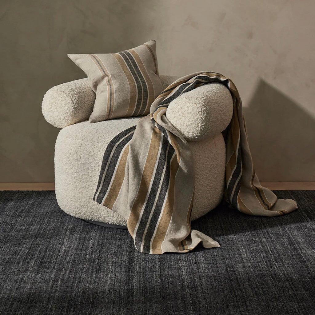 Dark grey rug and chair on a wooden floor.