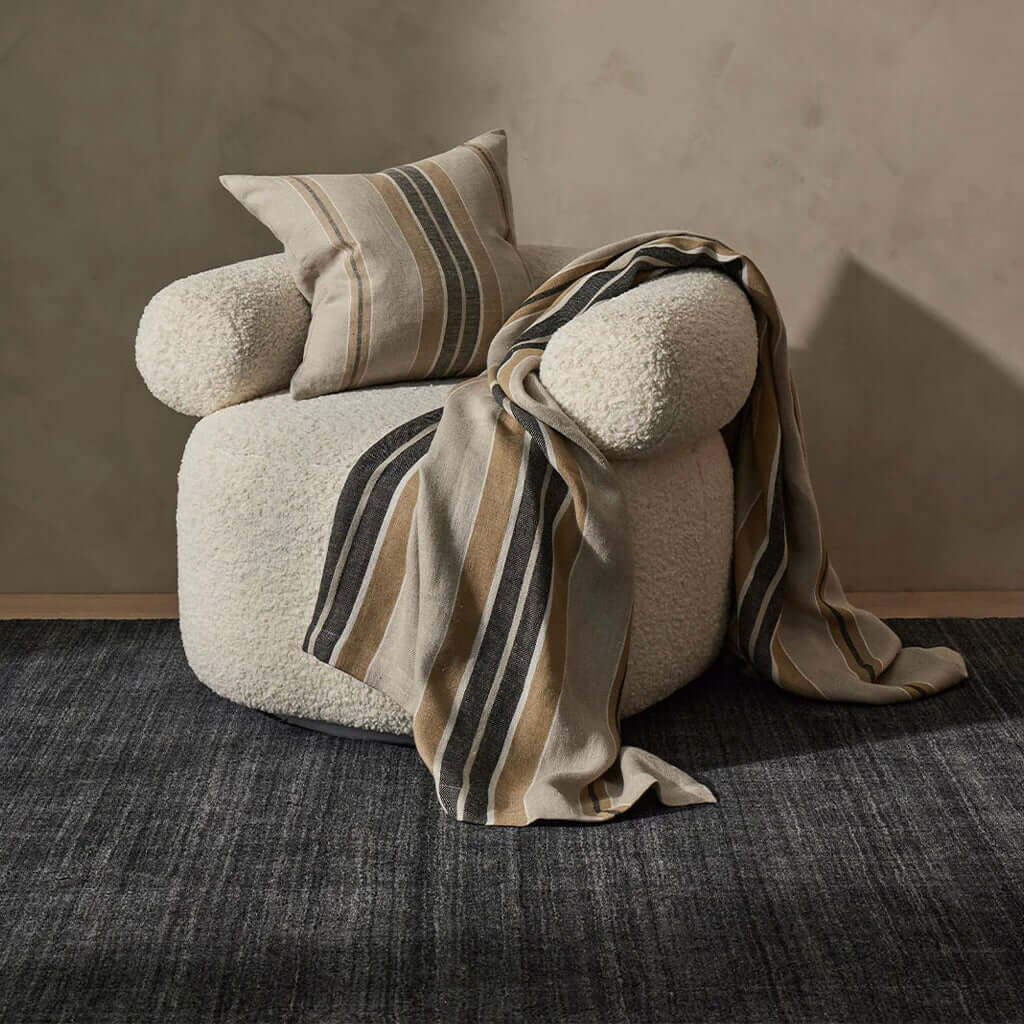 Dark grey rug and chair on a wooden floor.