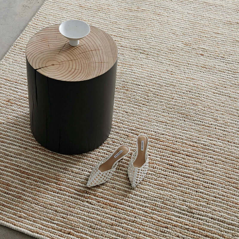 Beige rug with coffee table and shoes.