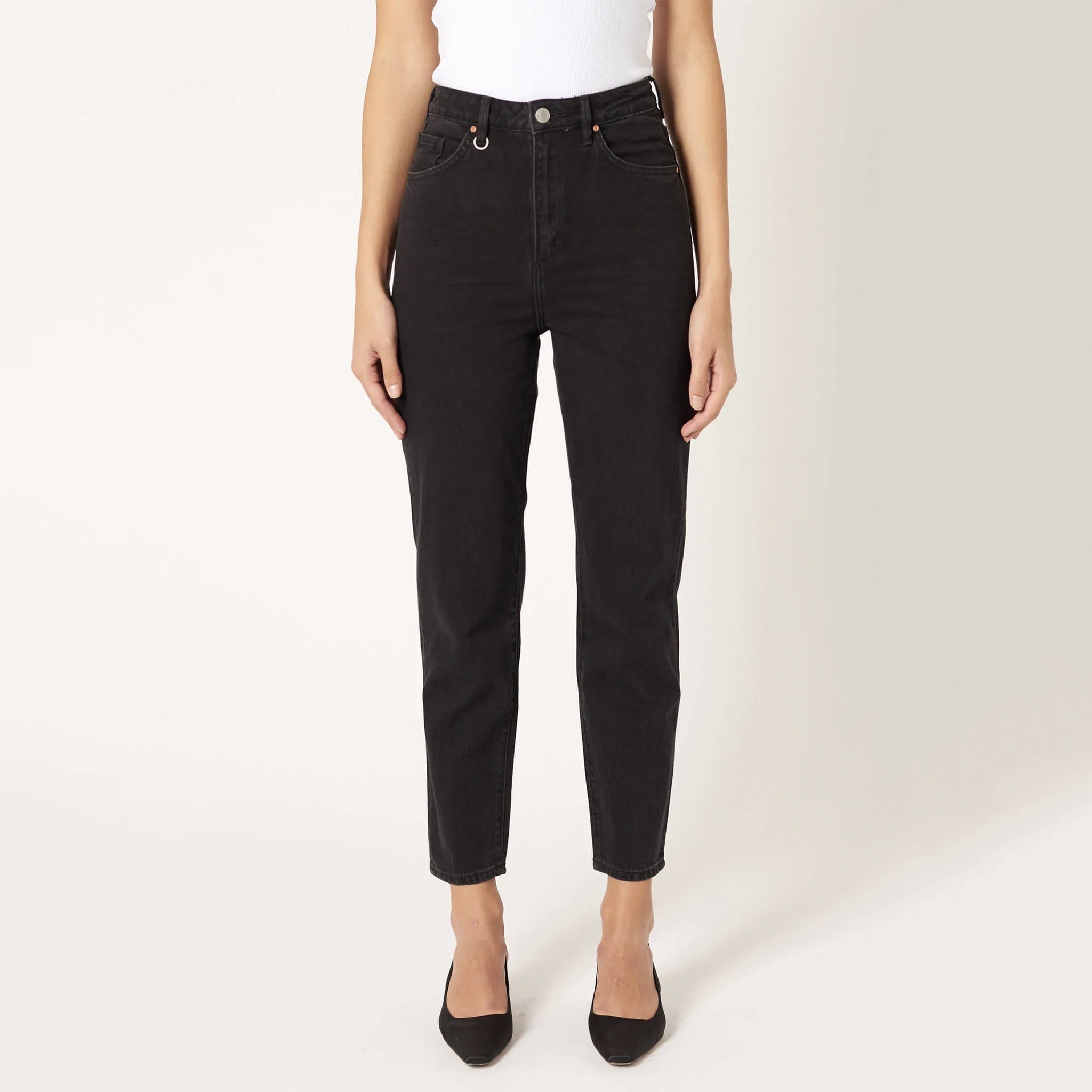 A person wearing a white cropped top and black jeans, standing against a white background.