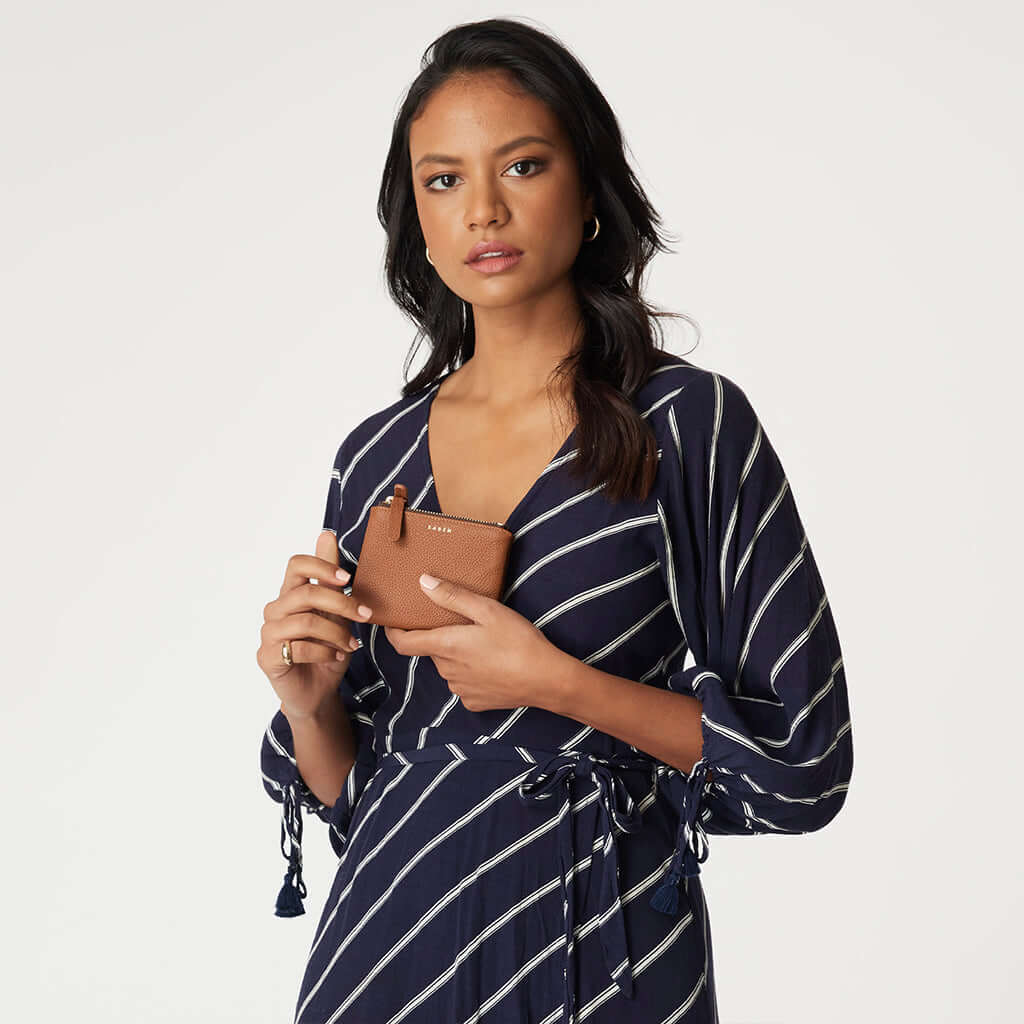 Saben Delilah Wallet - Tan in smooth tan leather with gold foil logo and zip coin pouch held by model