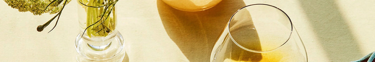 Broste Copenhagen glassware with a vase and amber tinted glass in sunlight, brand banner