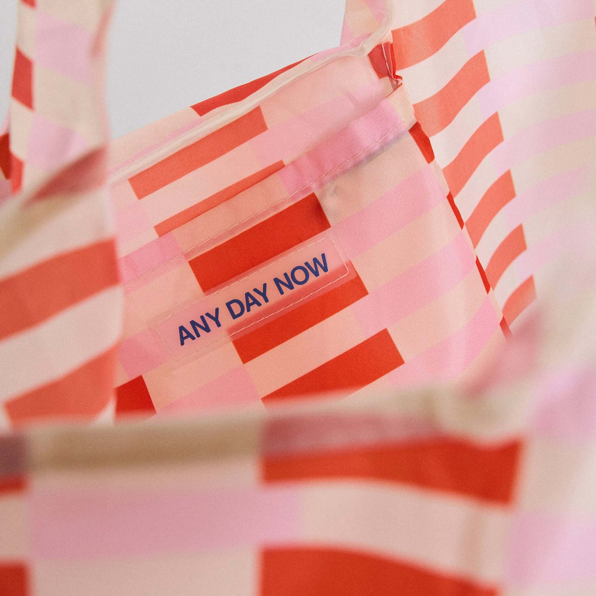 Inside view of the Any Day Now Any Where Tote - Pink & Red showing bold striped design and logo.