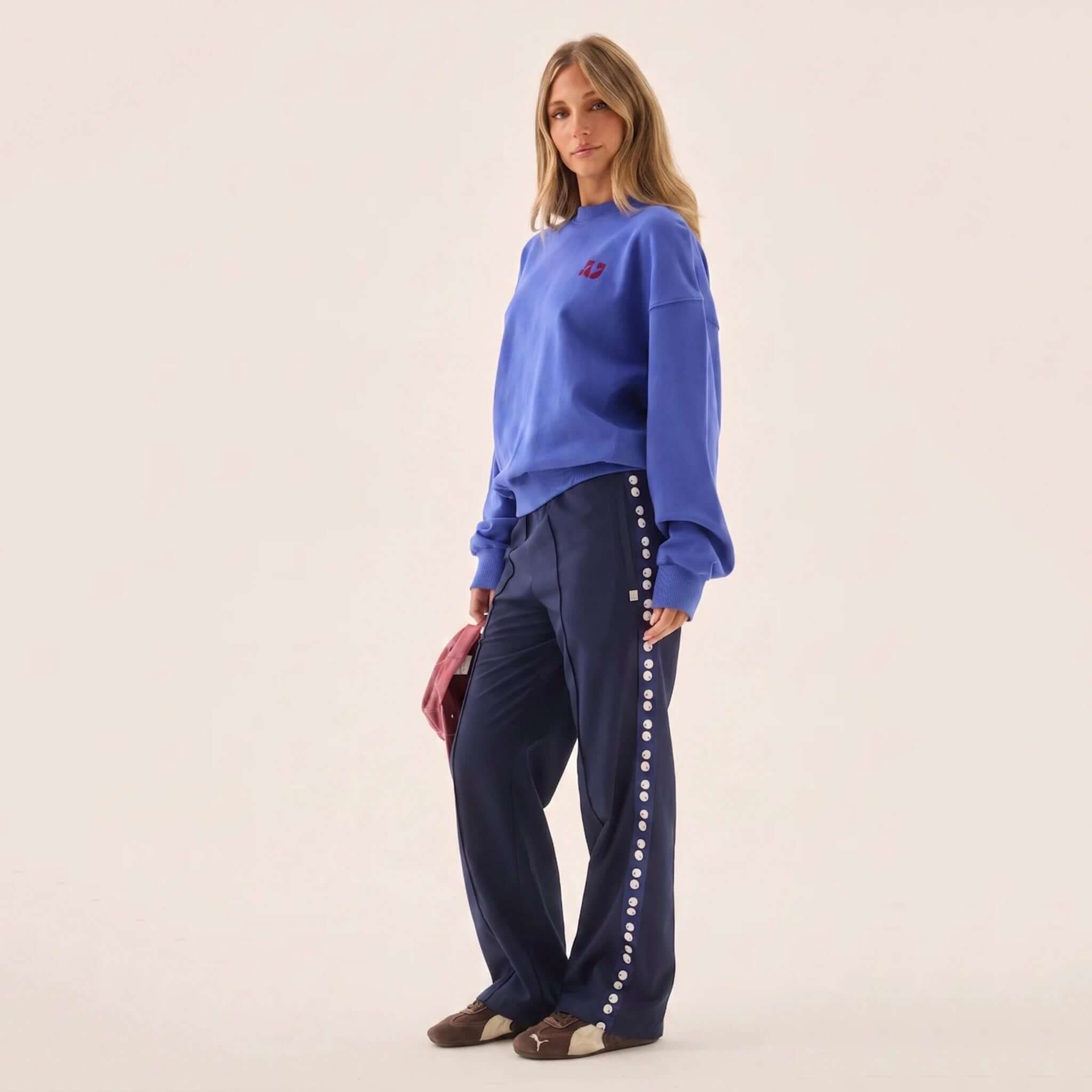 Model wearing Araminta James Pomodoro Twill Pants - Midnight Navy with a blue sweatshirt and stylish accessories.
