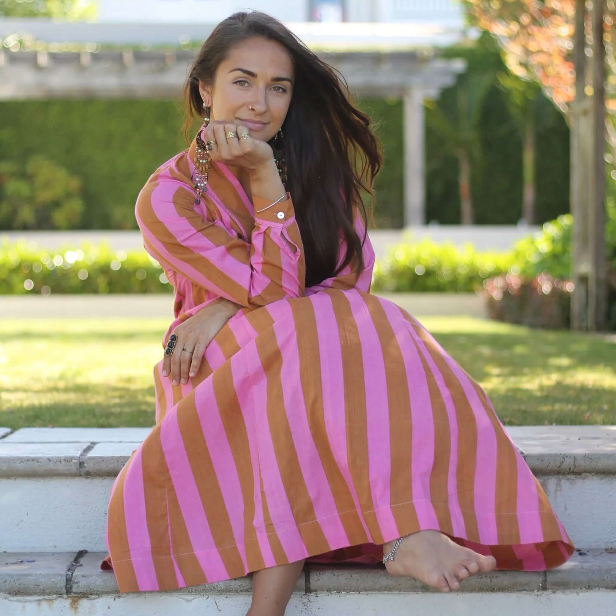Art In My Wardrobe Diana Dress - Pink worn by a woman sitting outdoors with a relaxed, stylish look.