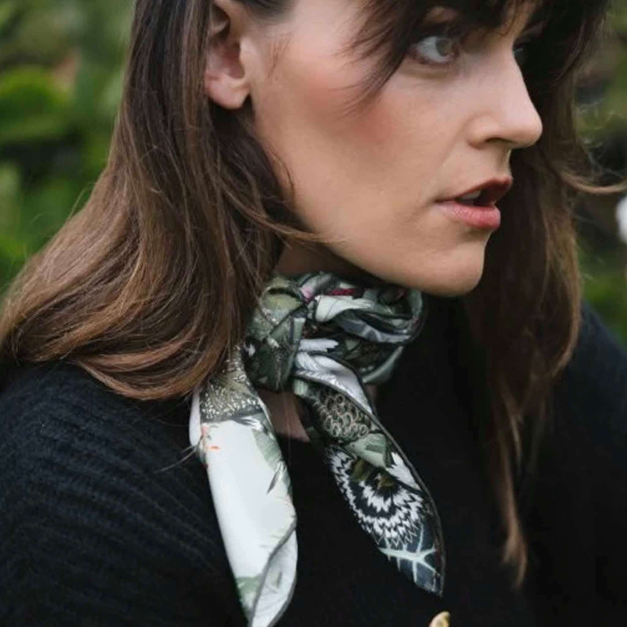 Alt Tag: Artifact Square Silk Scarf - Silva Noire worn as a neck scarf, green-toned botanical print with ivory and black florals