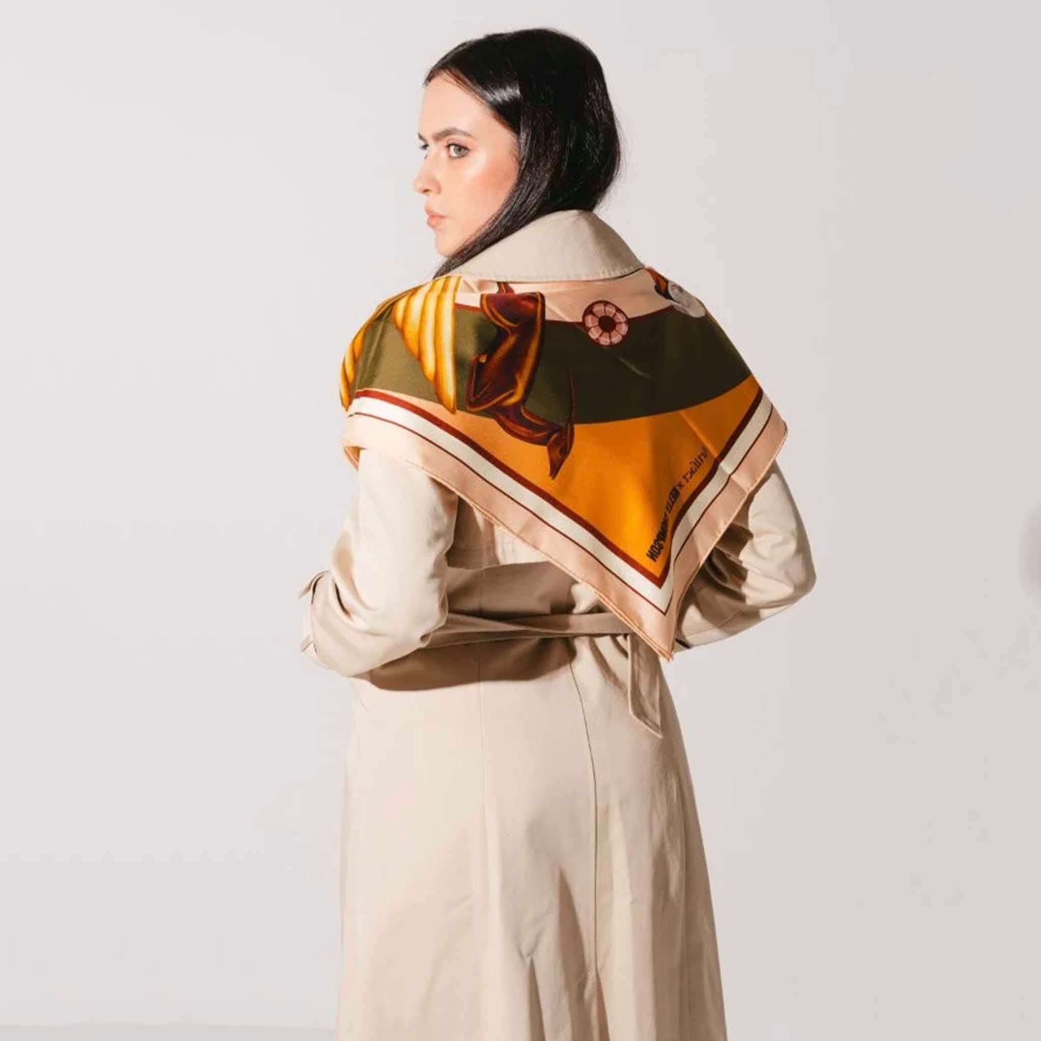 Alt Tag: Artifact x Kelly Thompson Square Silk Scarf - Gilded worn as shawl, double-sided silk twill with swan motif in gold tones