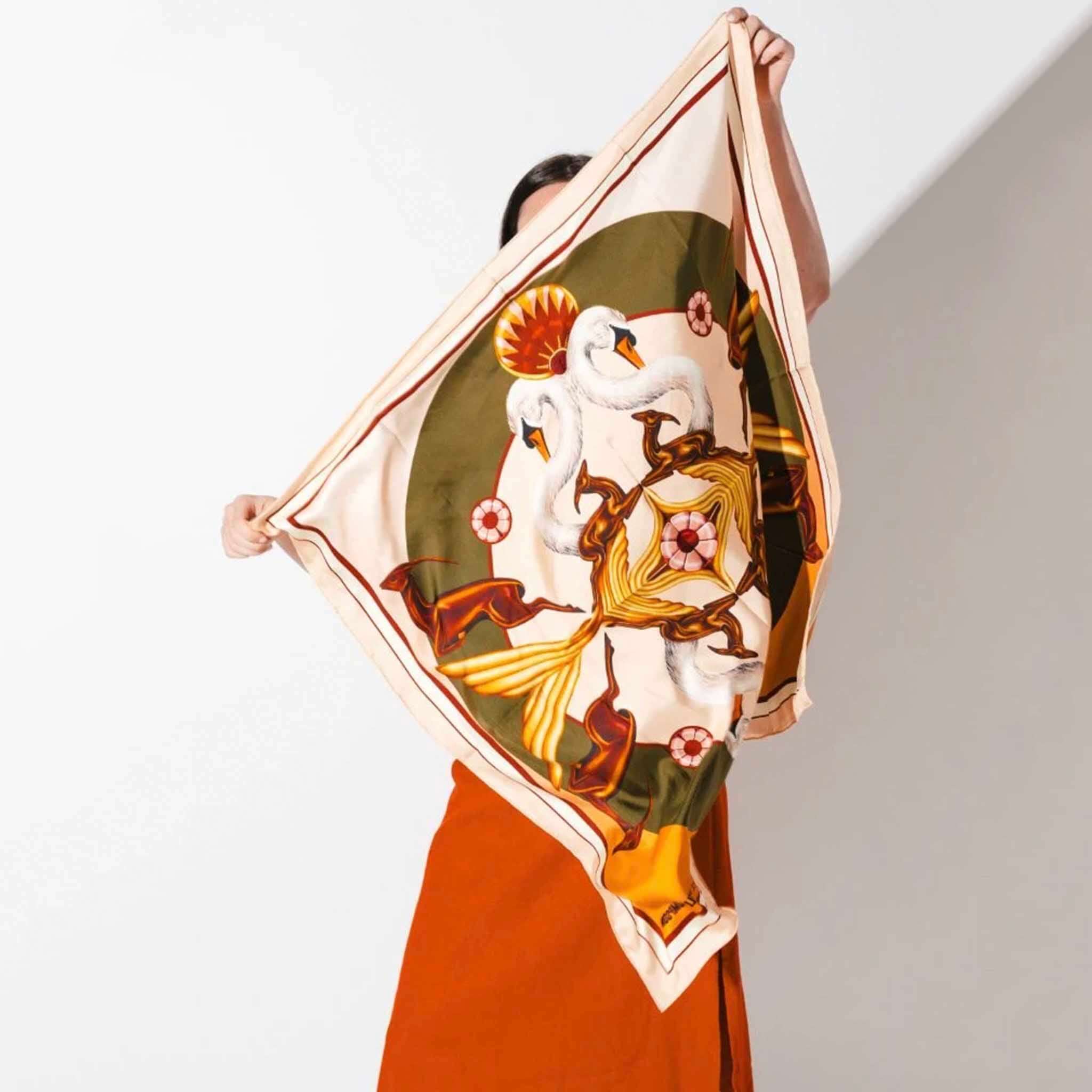 Artifact x Kelly Thompson Square Silk Scarf - Gilded held up, square silk twill scarf with swan motif and gilded abstract symmetry