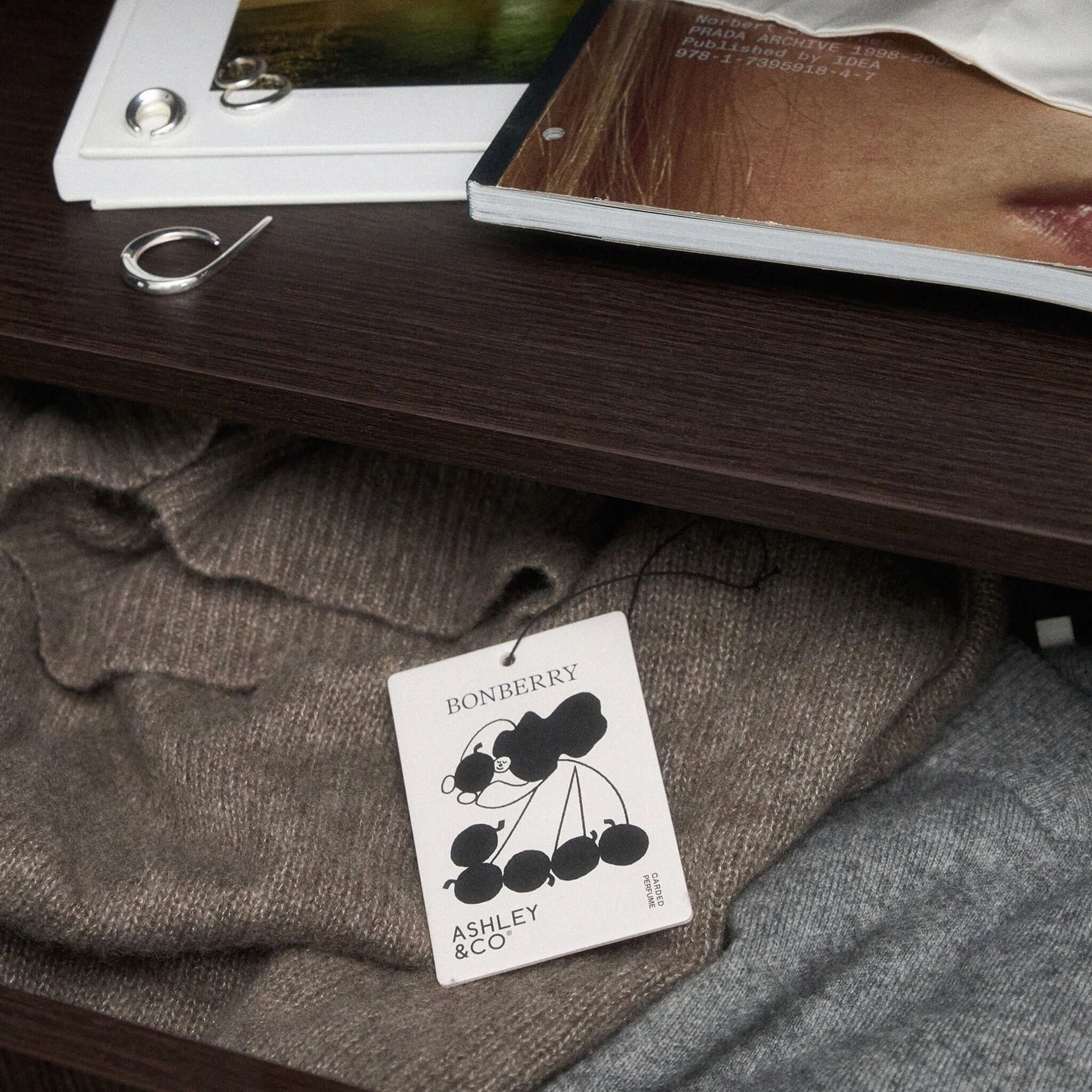 Alt Tag: Ashley & Co Carded Perfume Air Freshener - Bonberry carded perfume scent sachet in drawer with folded knitwear