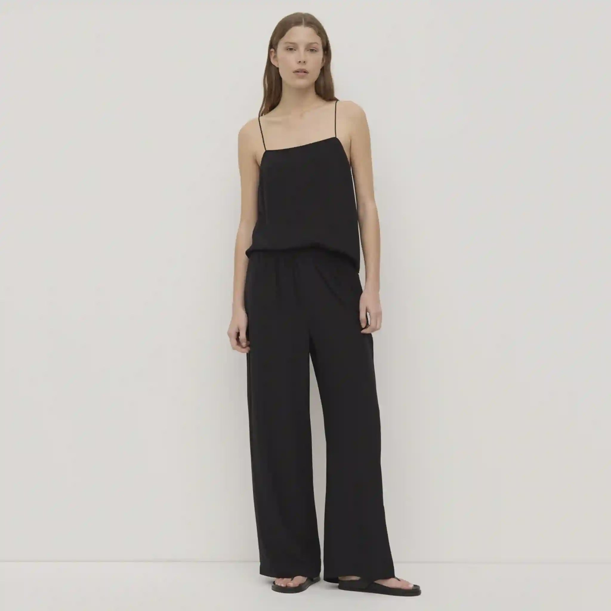 Woman wearing a black jumpsuit on a plain background
