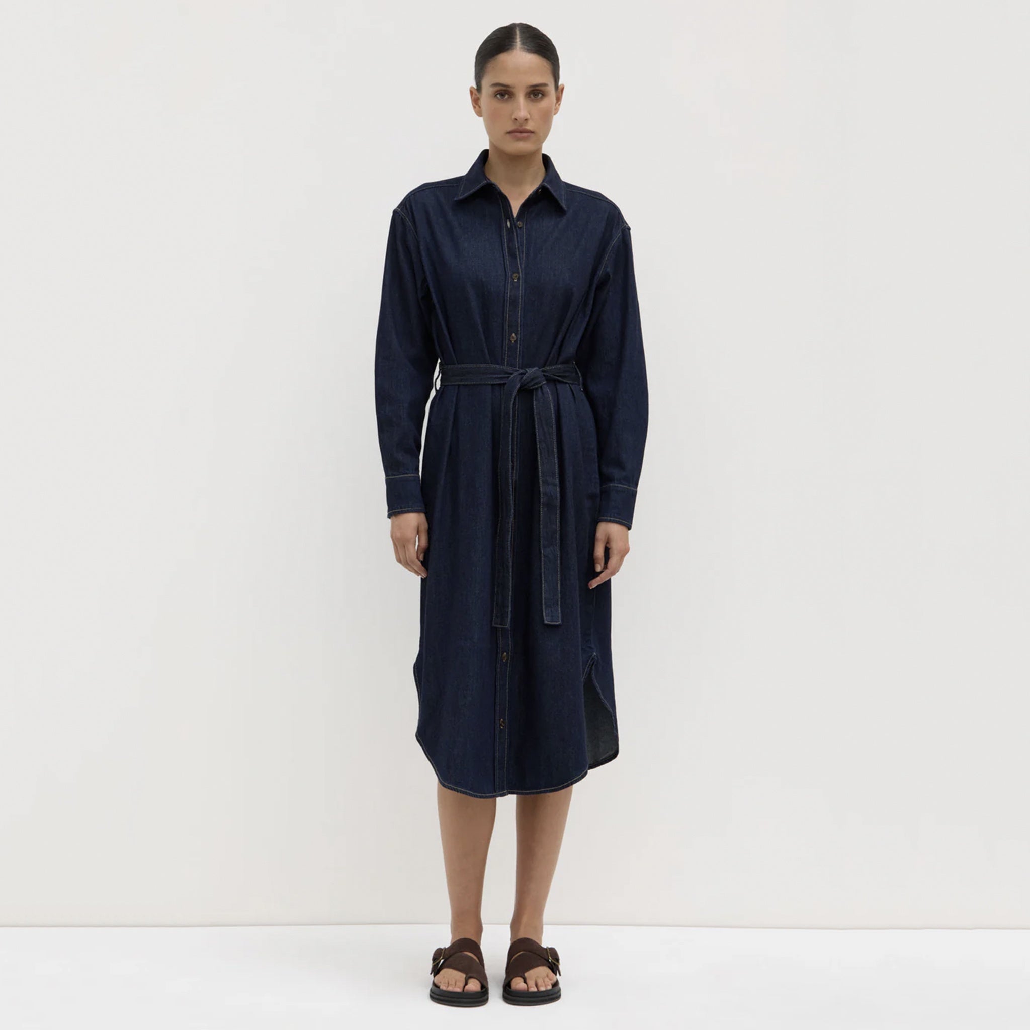 Woman wearing a navy blue dress with a belt on a white background