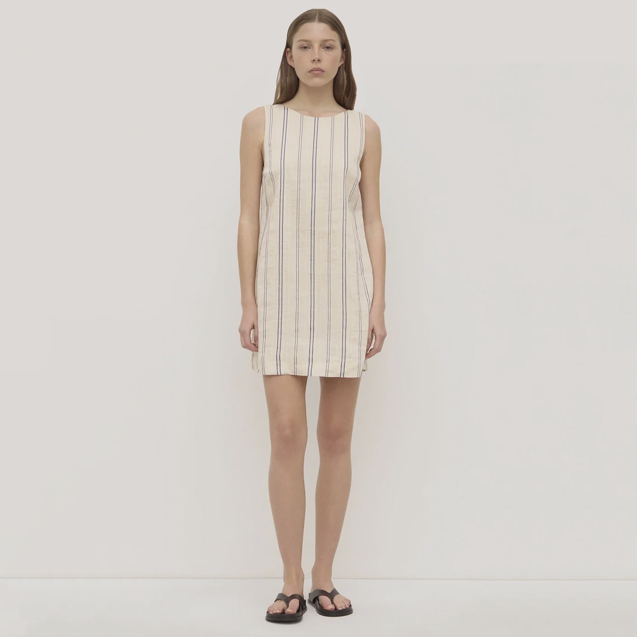 Woman wearing a sleeveless striped dress on a plain background
