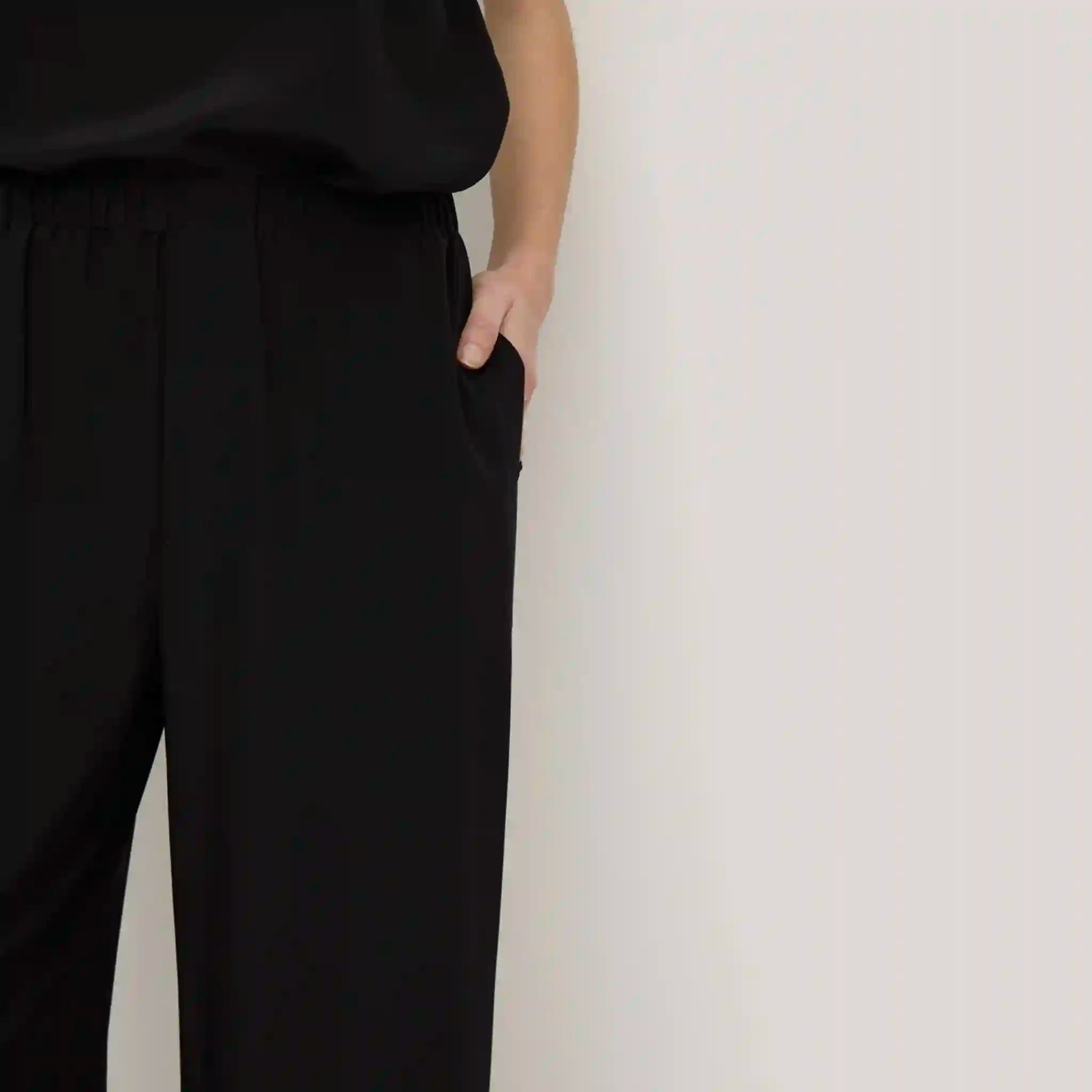 Person wearing black pants against a white background