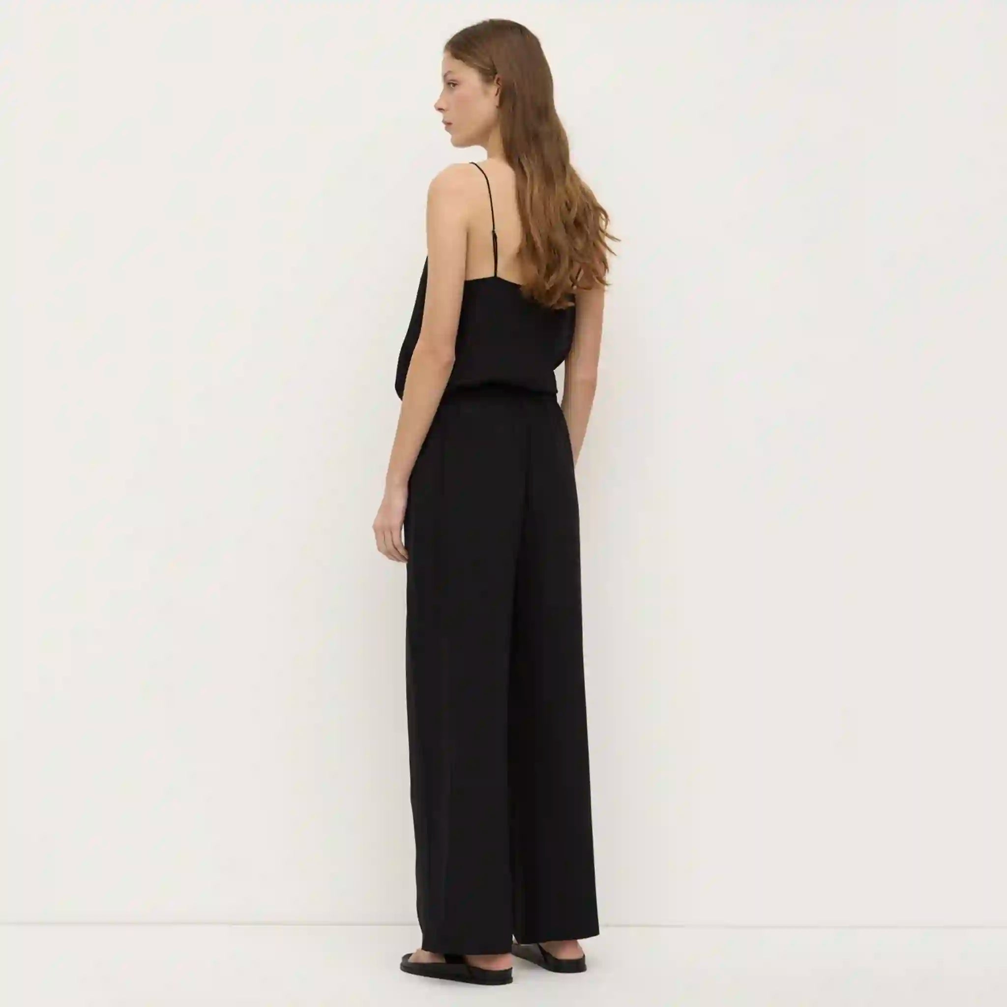 Woman wearing a black jumpsuit against a white background