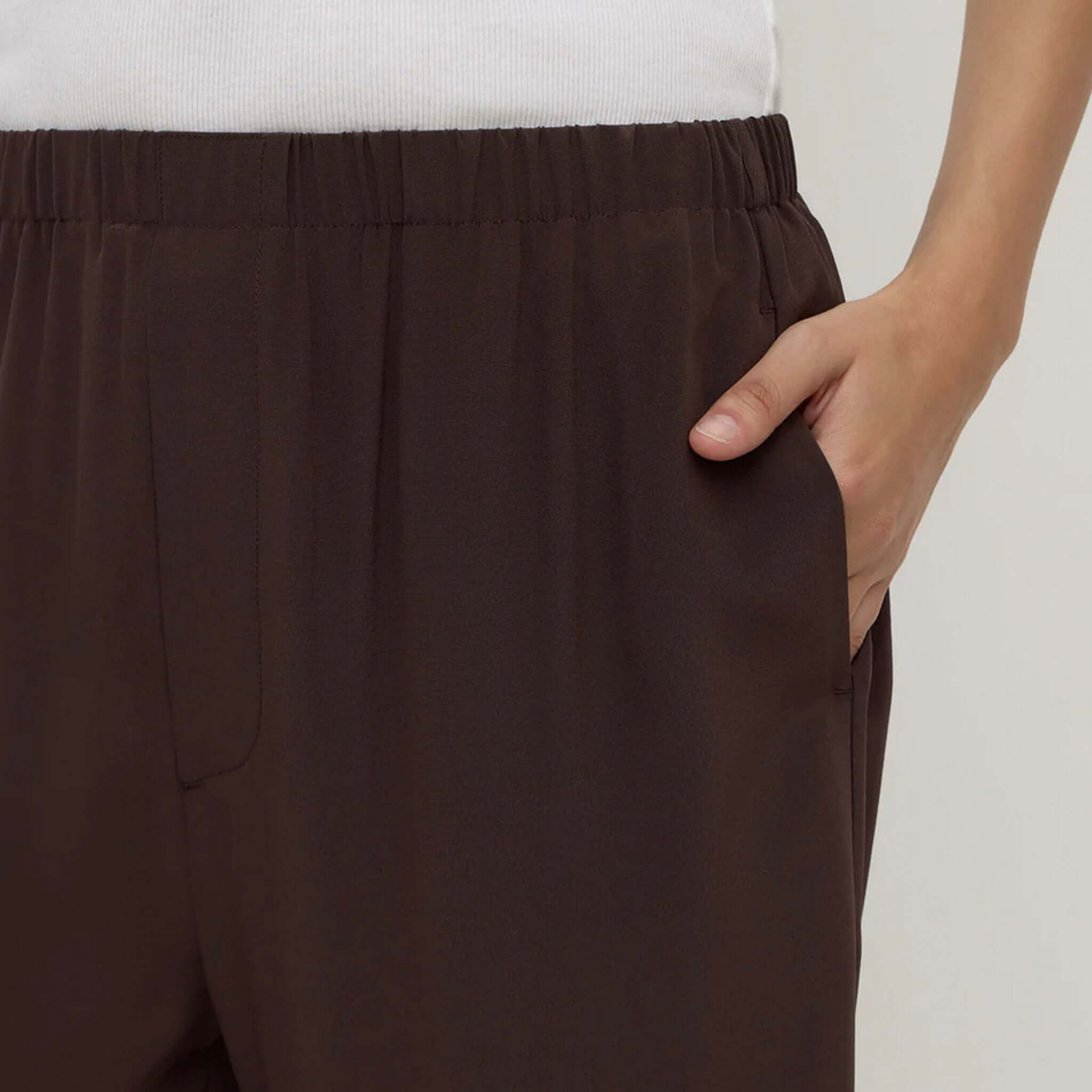Alt Tag: Assembly Label Betty Silk Pants - Ganache close-up of ganache brown silk straight-leg pants with elastic waistband and pocket detail