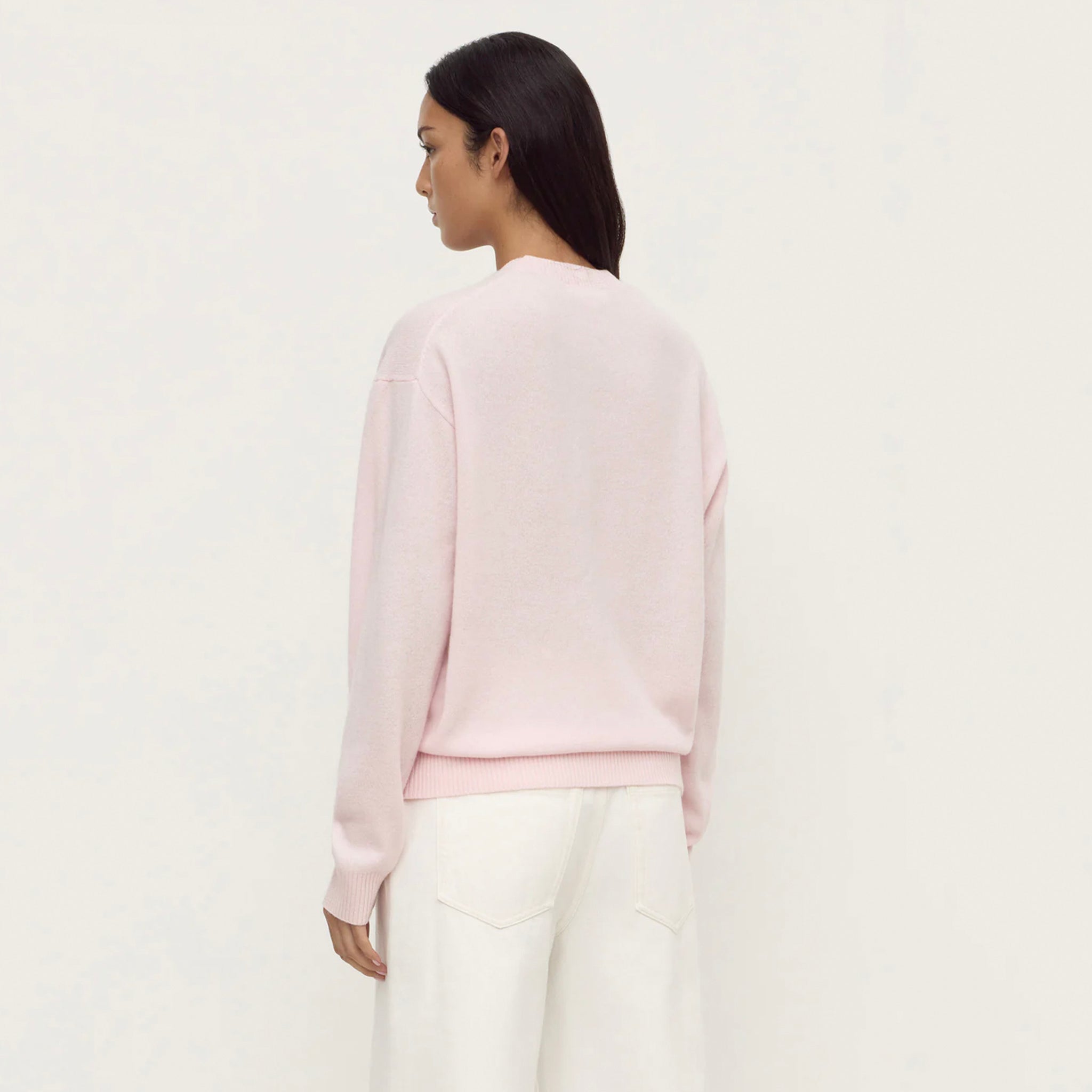 Back view of a woman wearing the Assembly Label Carter Brushed Merino Wool Sweater - Floss in a soft pink color.