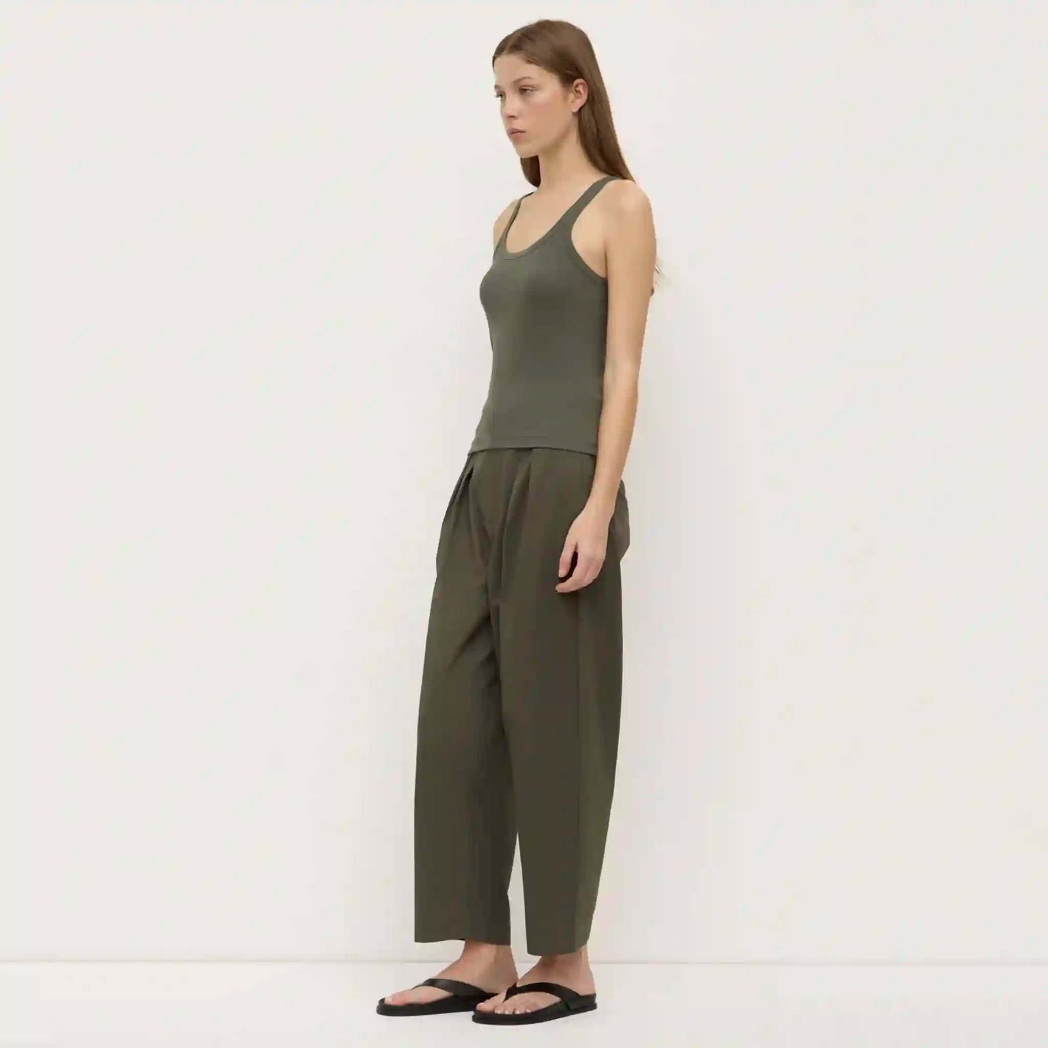 Woman wearing a green tank top and pants on a white background
