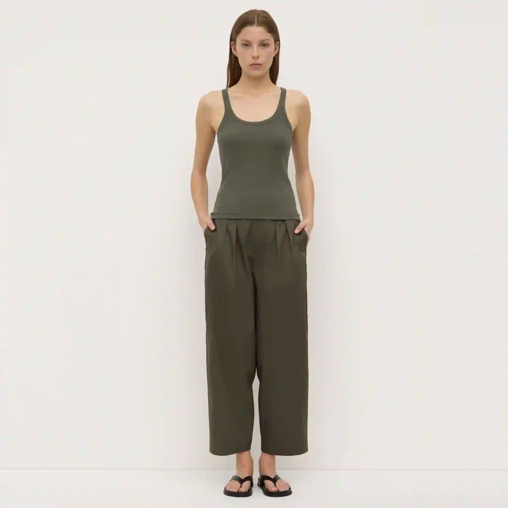Woman wearing a green tank top and wide-leg pants on a white background