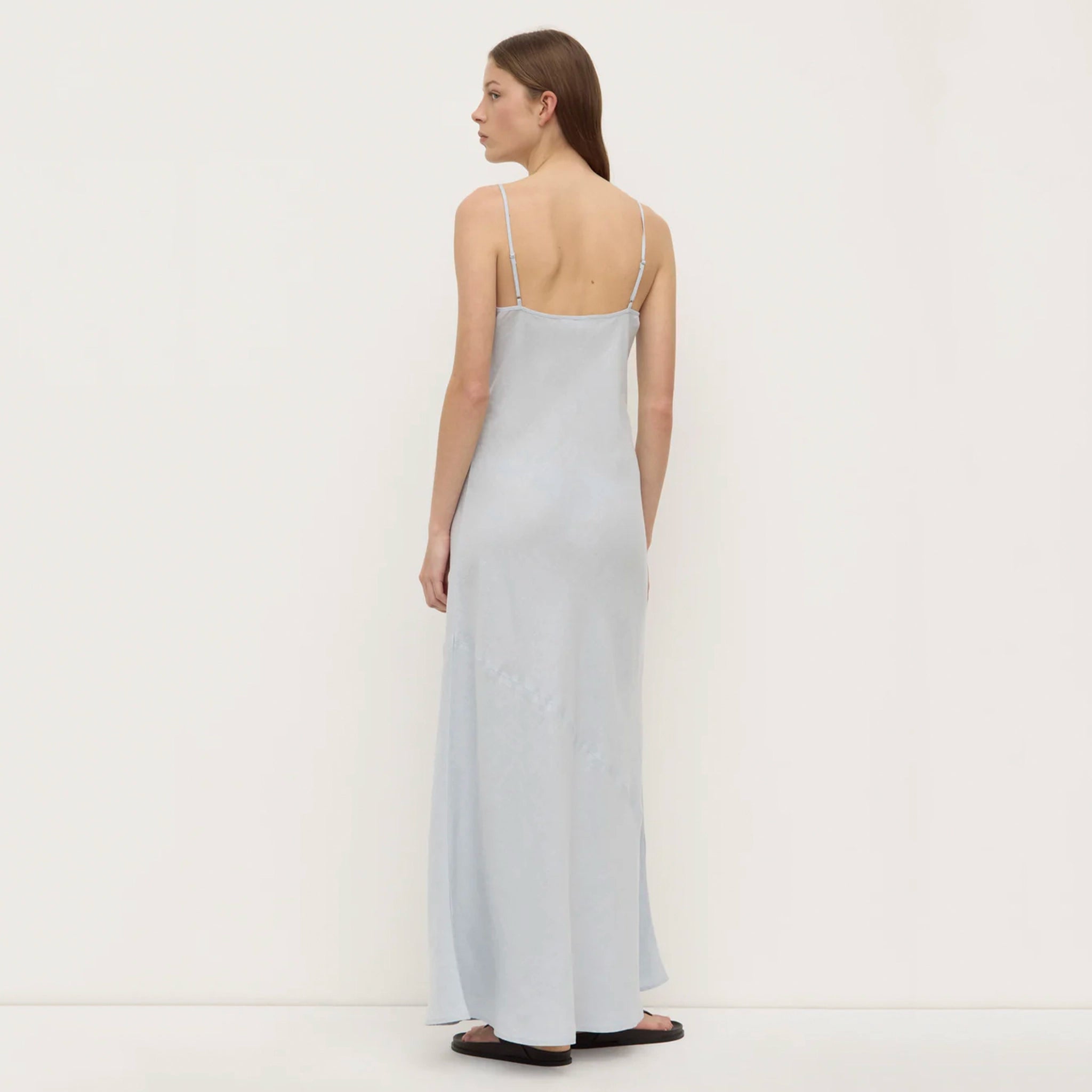 Woman wearing a light blue slip dress on a white background