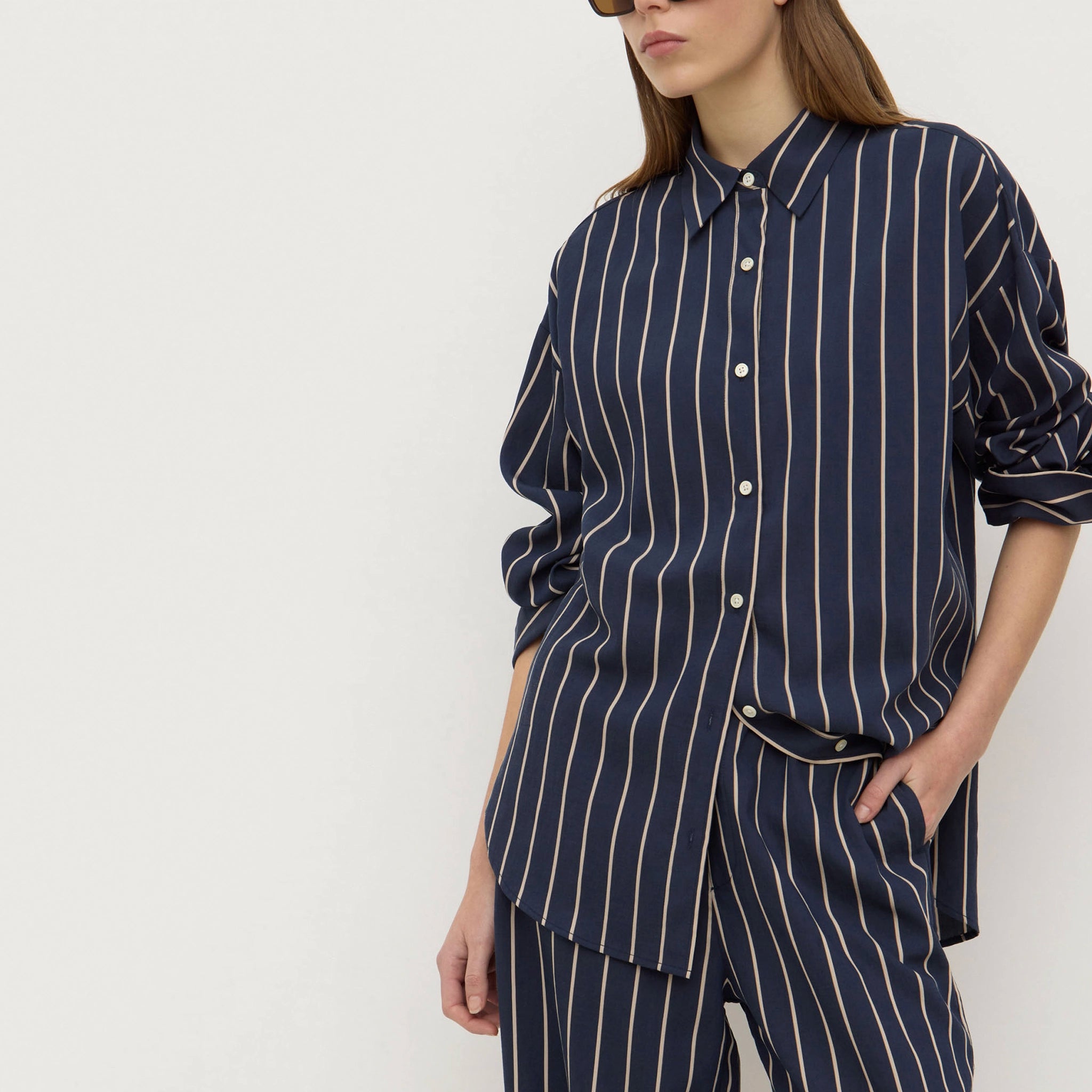 Person wearing a navy pinstripe shirt and pants on a white background