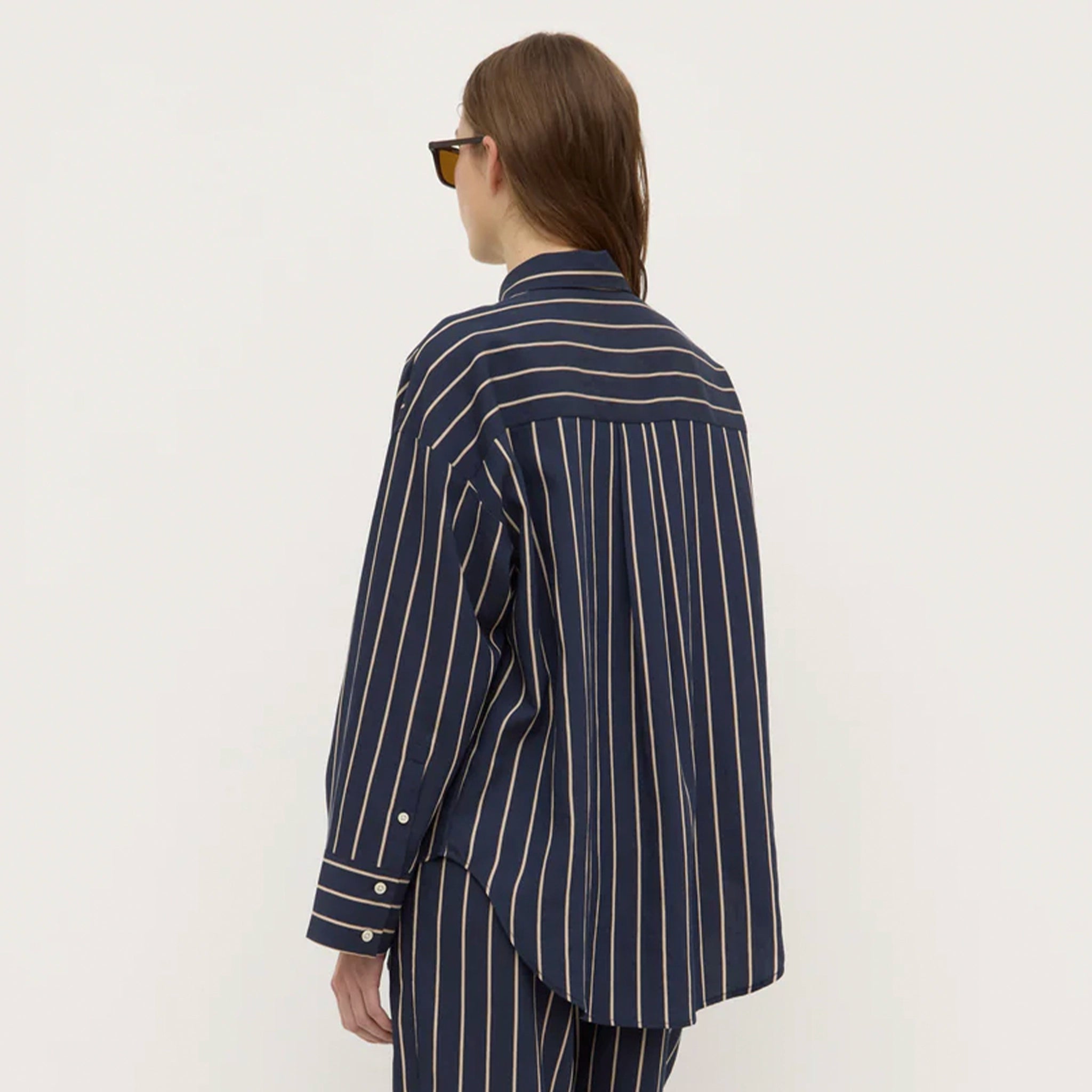 Person wearing a navy striped shirt and pants on a white background