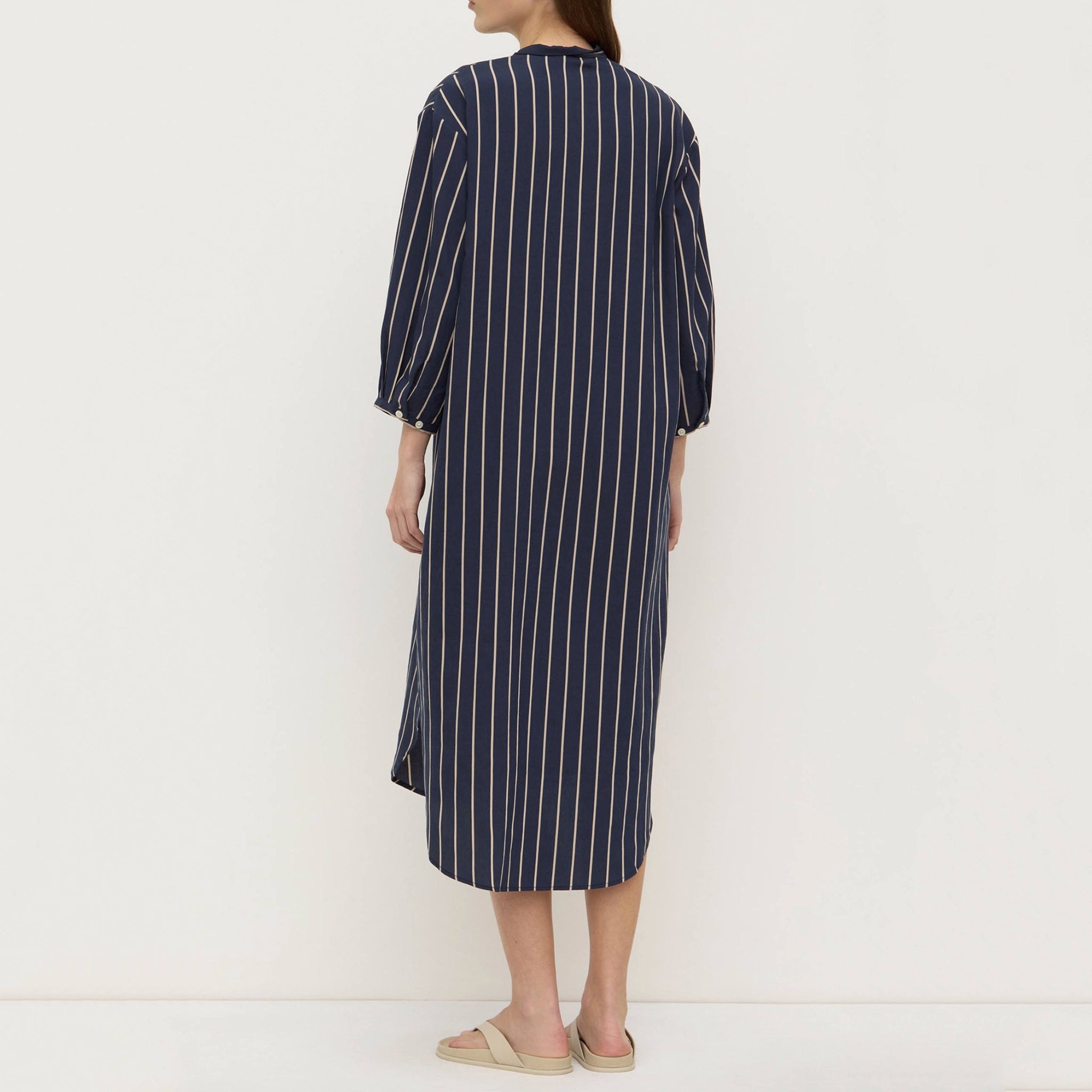 Person wearing a navy and white striped dress on a plain background