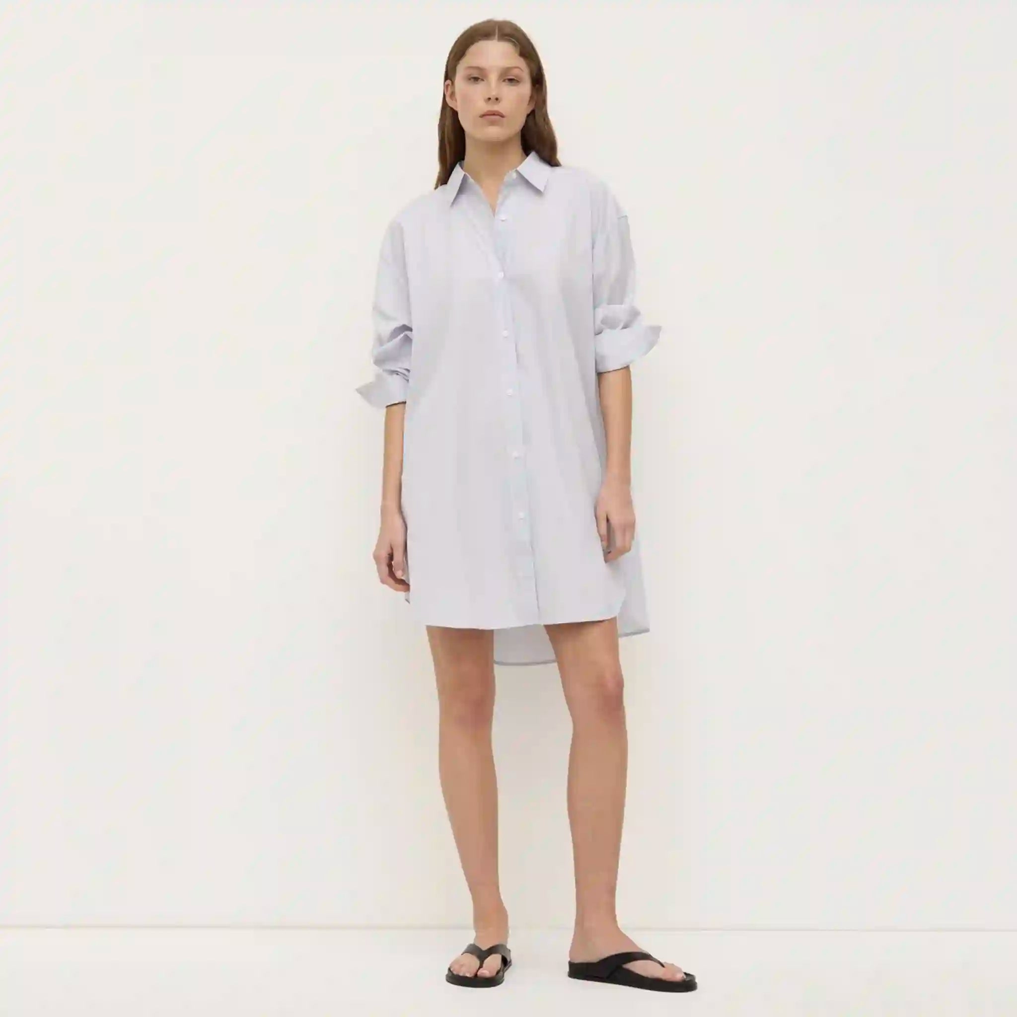 Woman wearing a light blue shirt dress against a white background