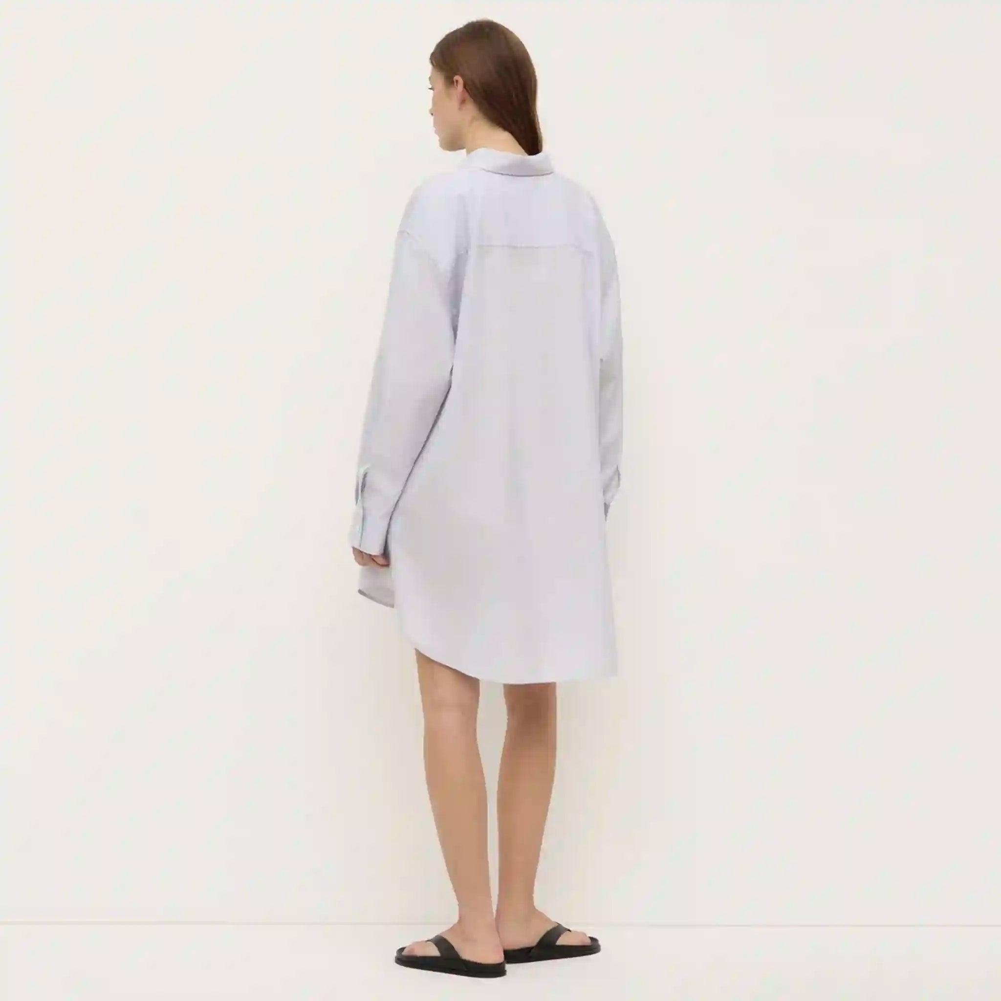 Person wearing a light gray dress against a white background