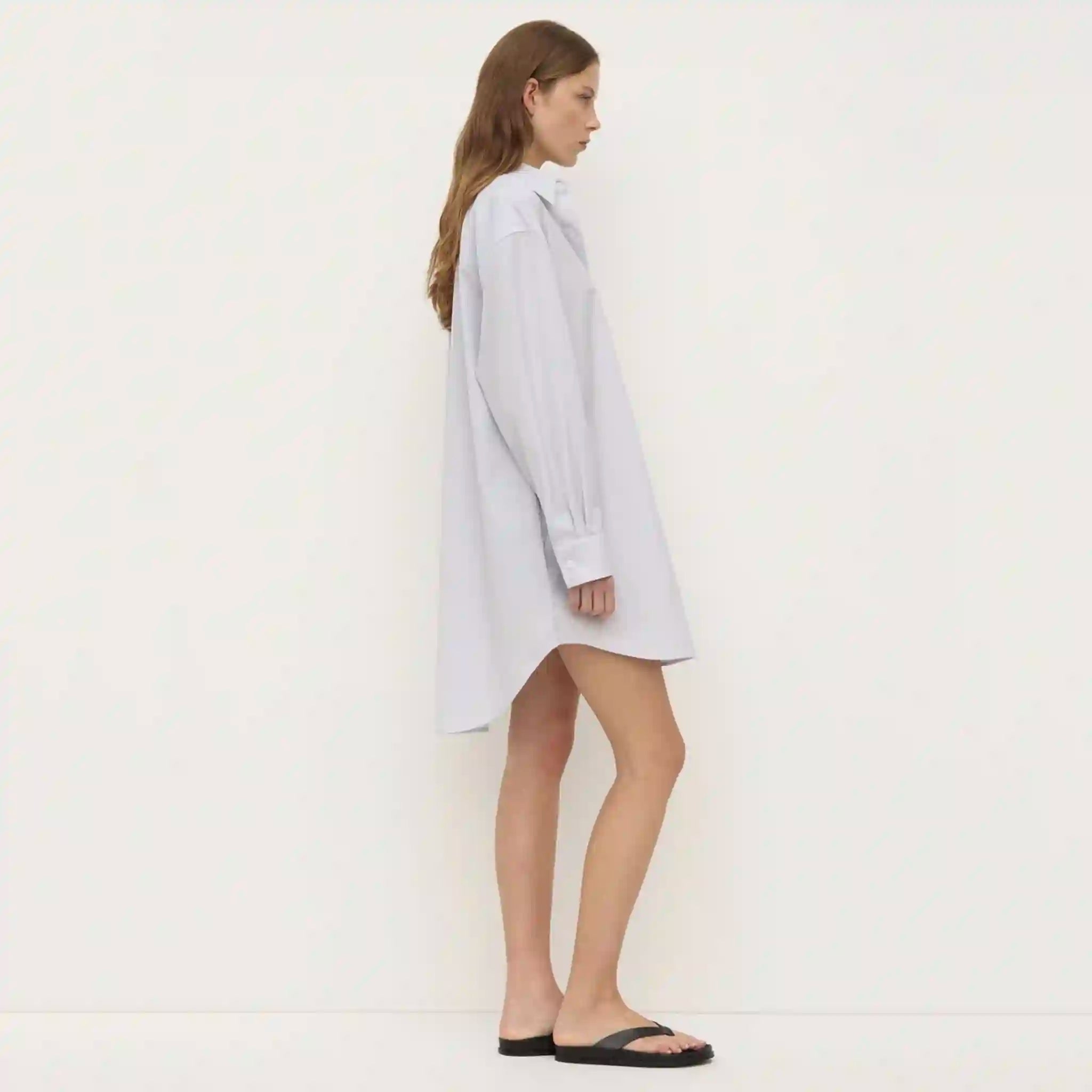 Woman wearing a light blue shirt dress on a white background