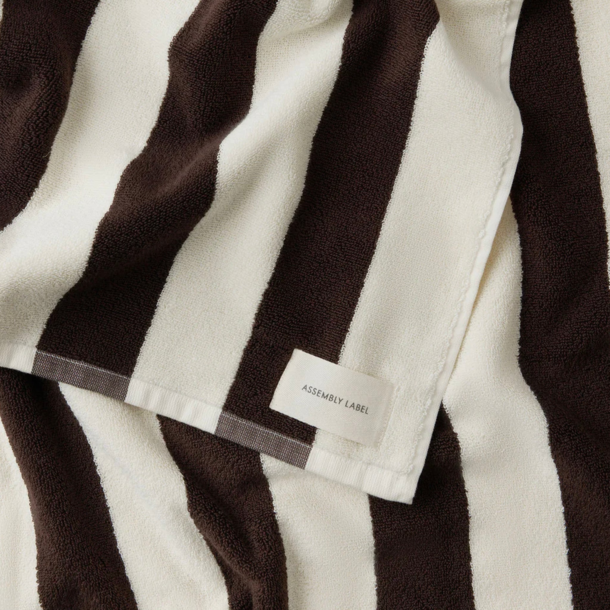 Close-up of a brown and white striped beach towel with a label.