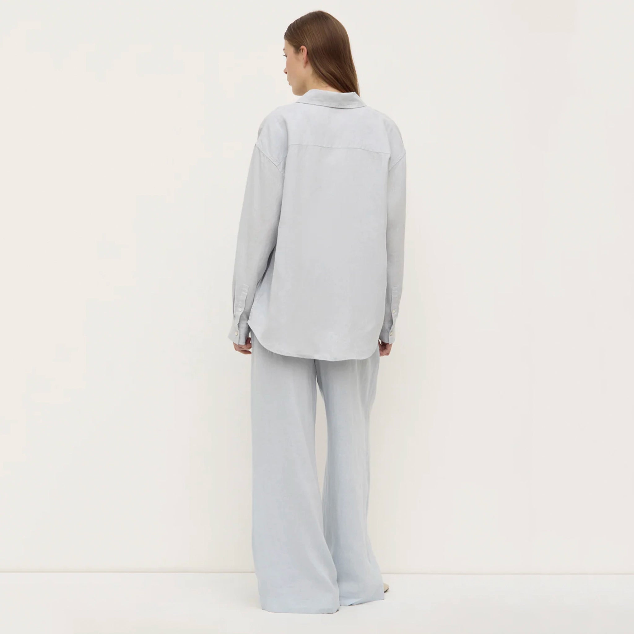 Woman wearing a light gray shirt standing against a white background