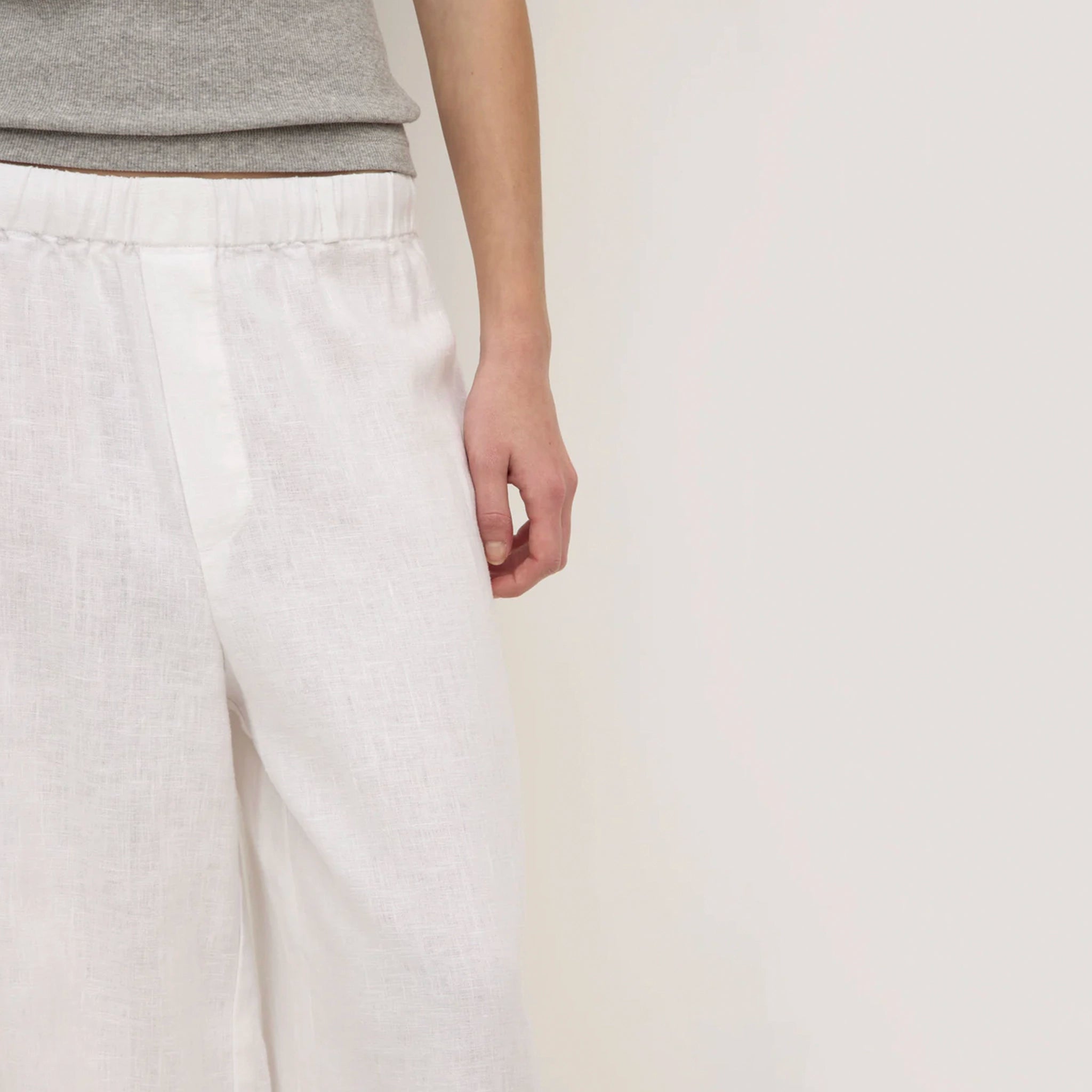 Person wearing light gray pants and a gray top on a plain background