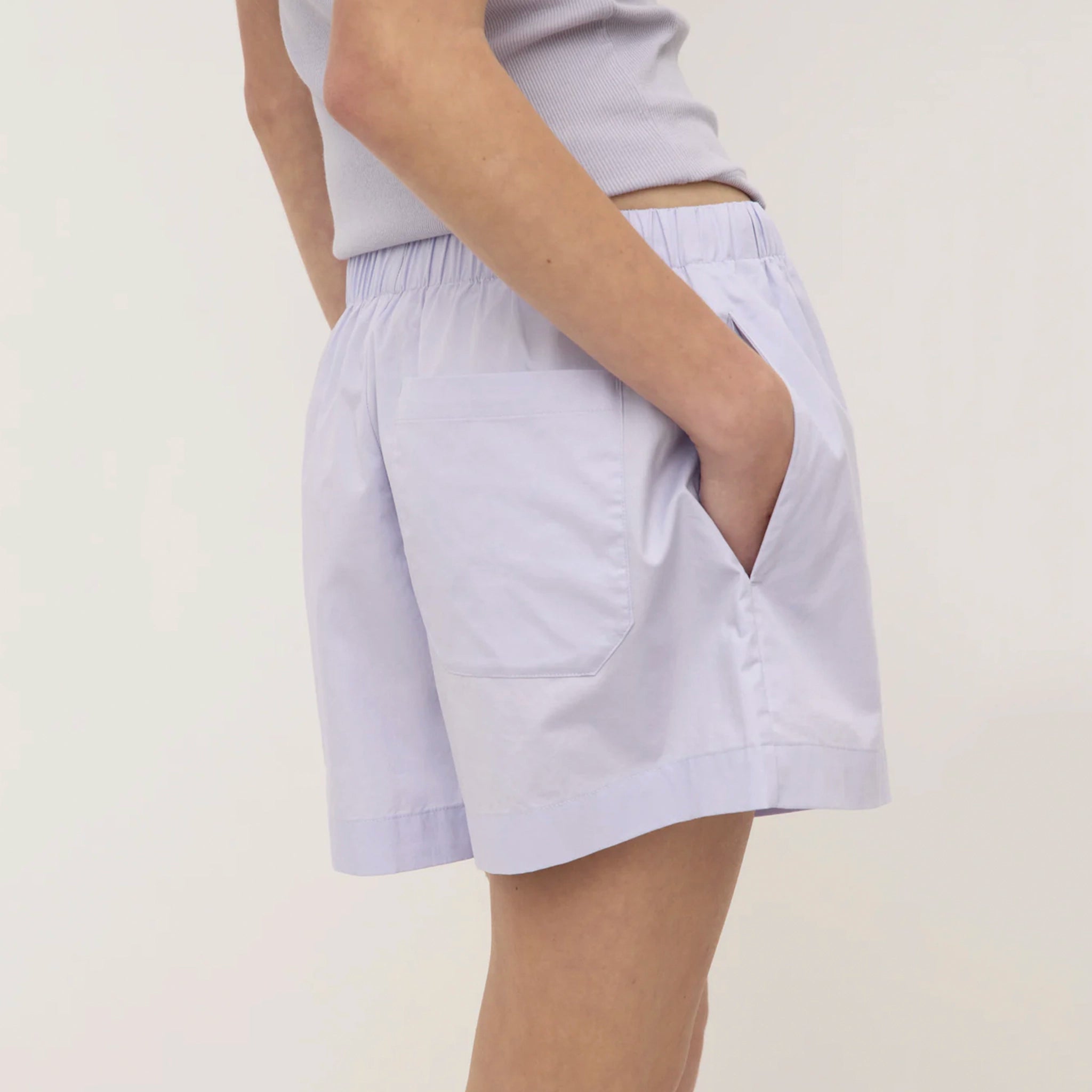 Person wearing light purple shorts on a plain background