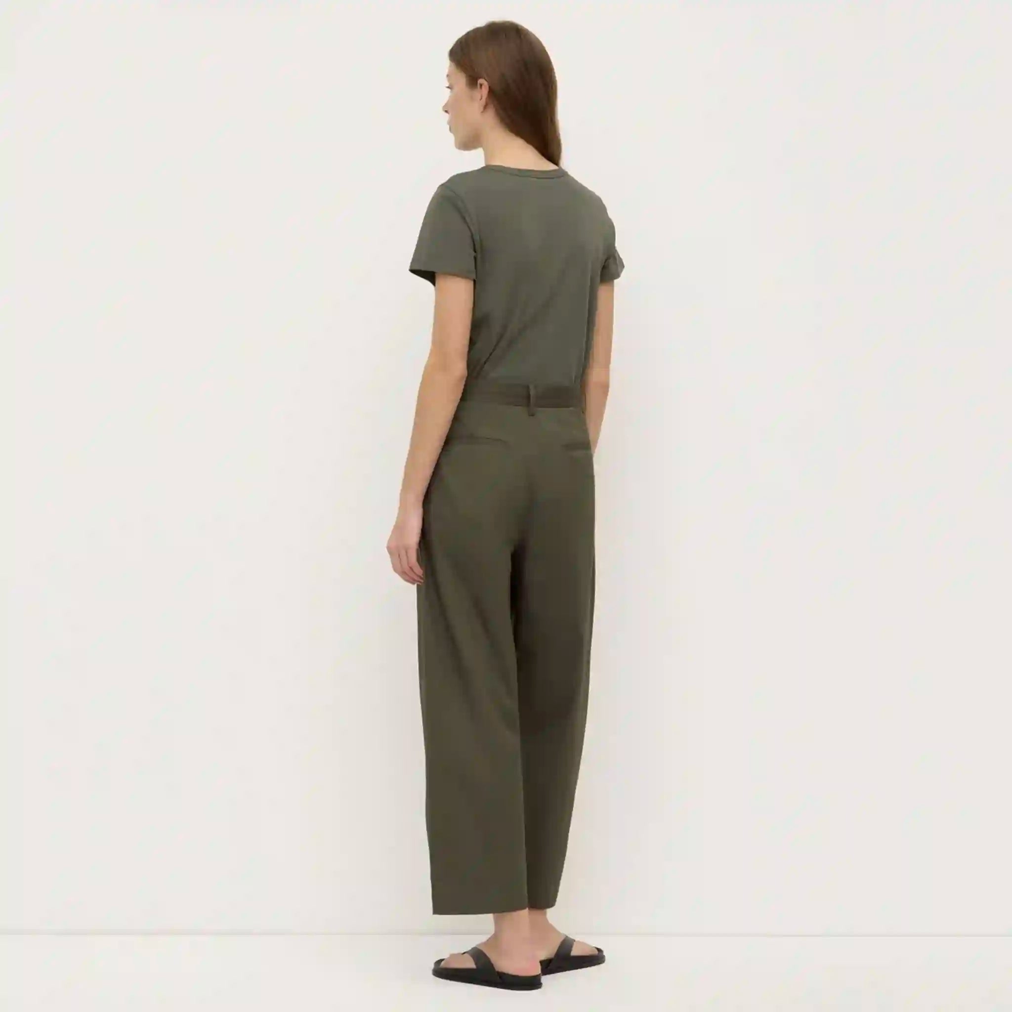 Person wearing a green jumpsuit standing against a white background