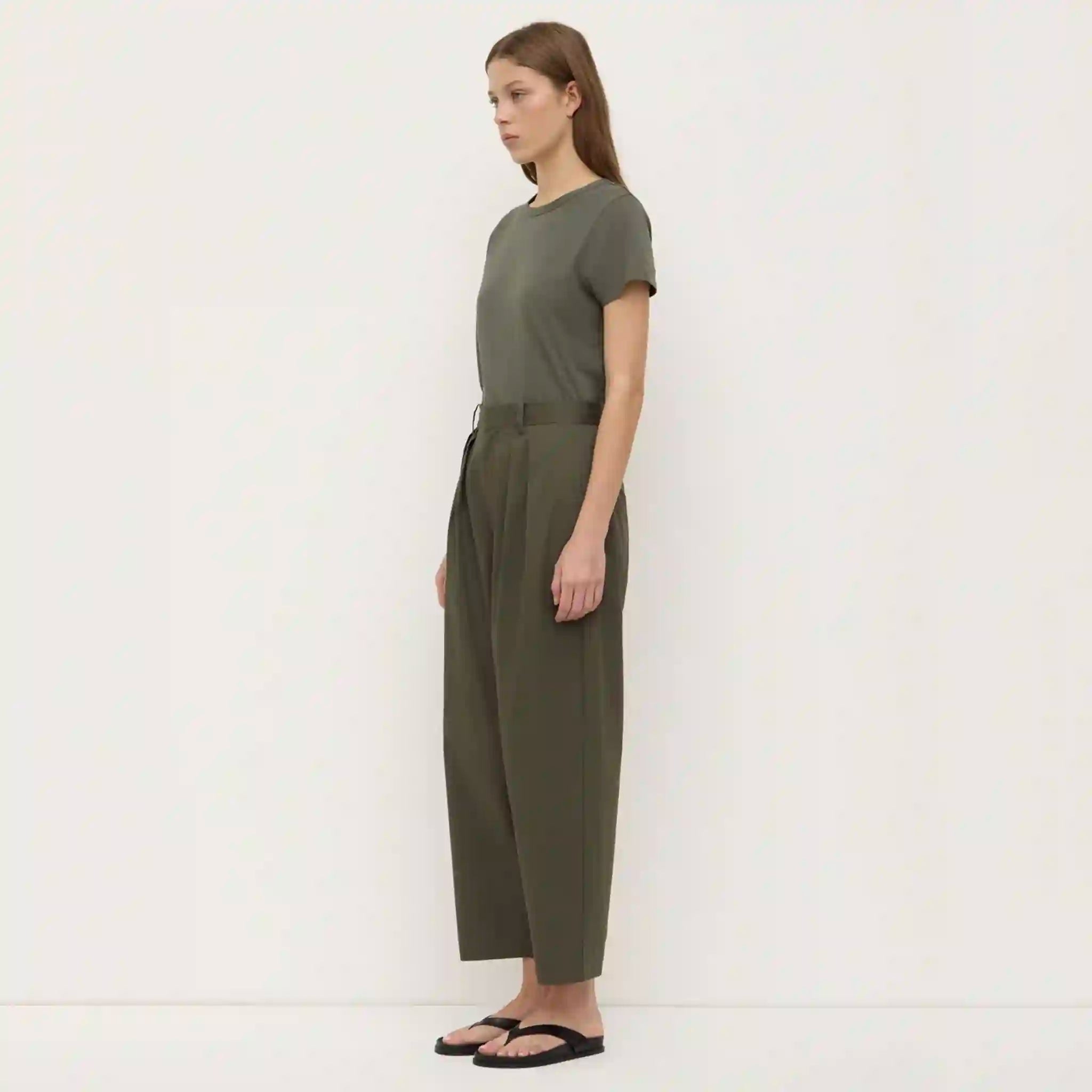 Woman wearing a green jumpsuit standing against a white background