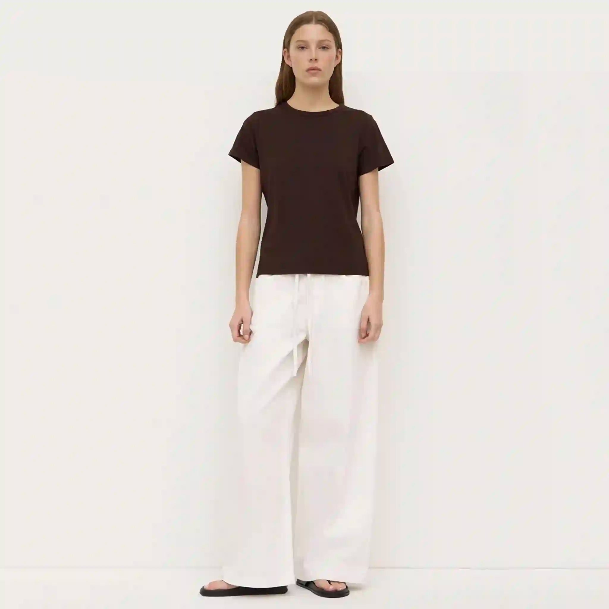 Person wearing a black t-shirt and white pants on a plain background
