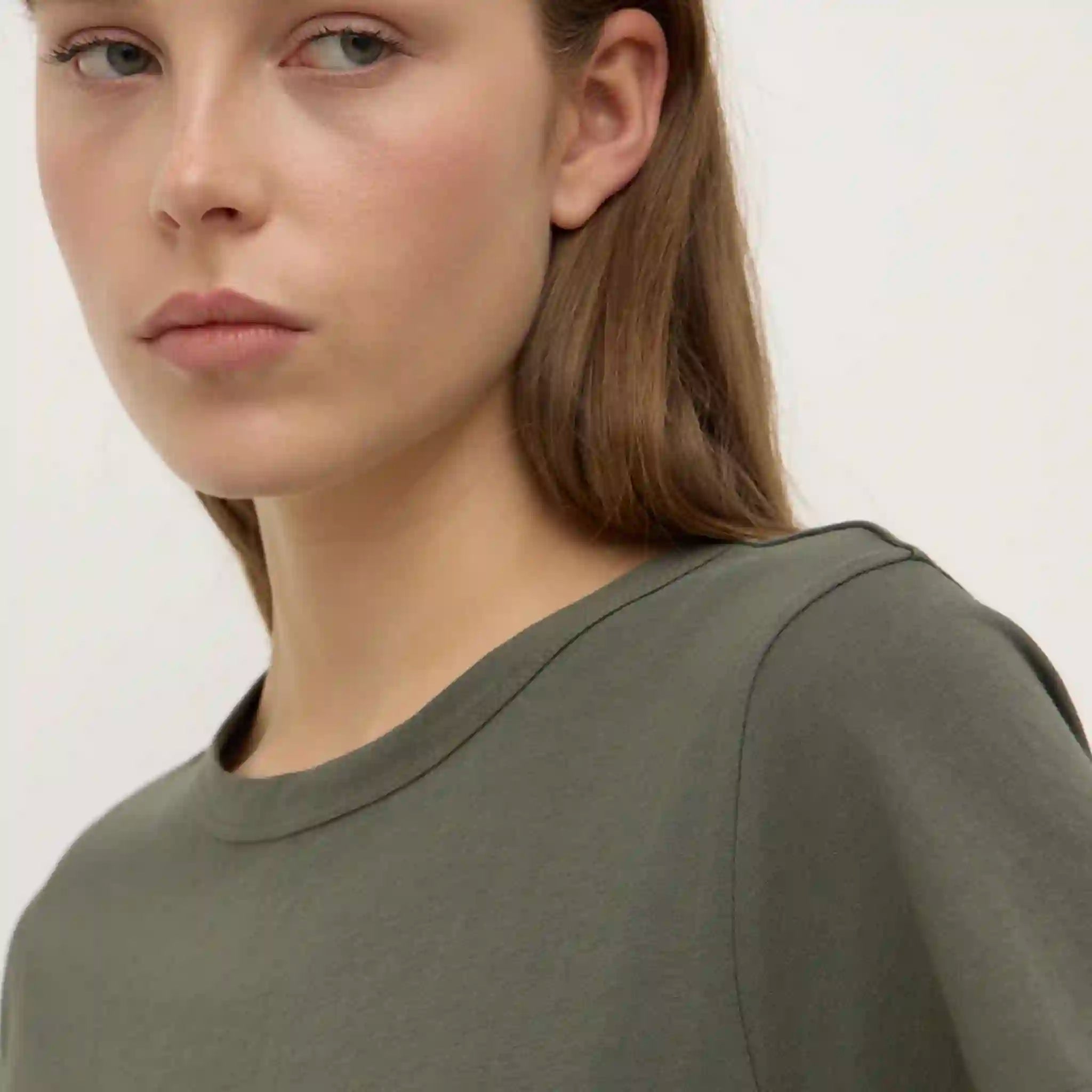 Person wearing a green shirt against a plain background