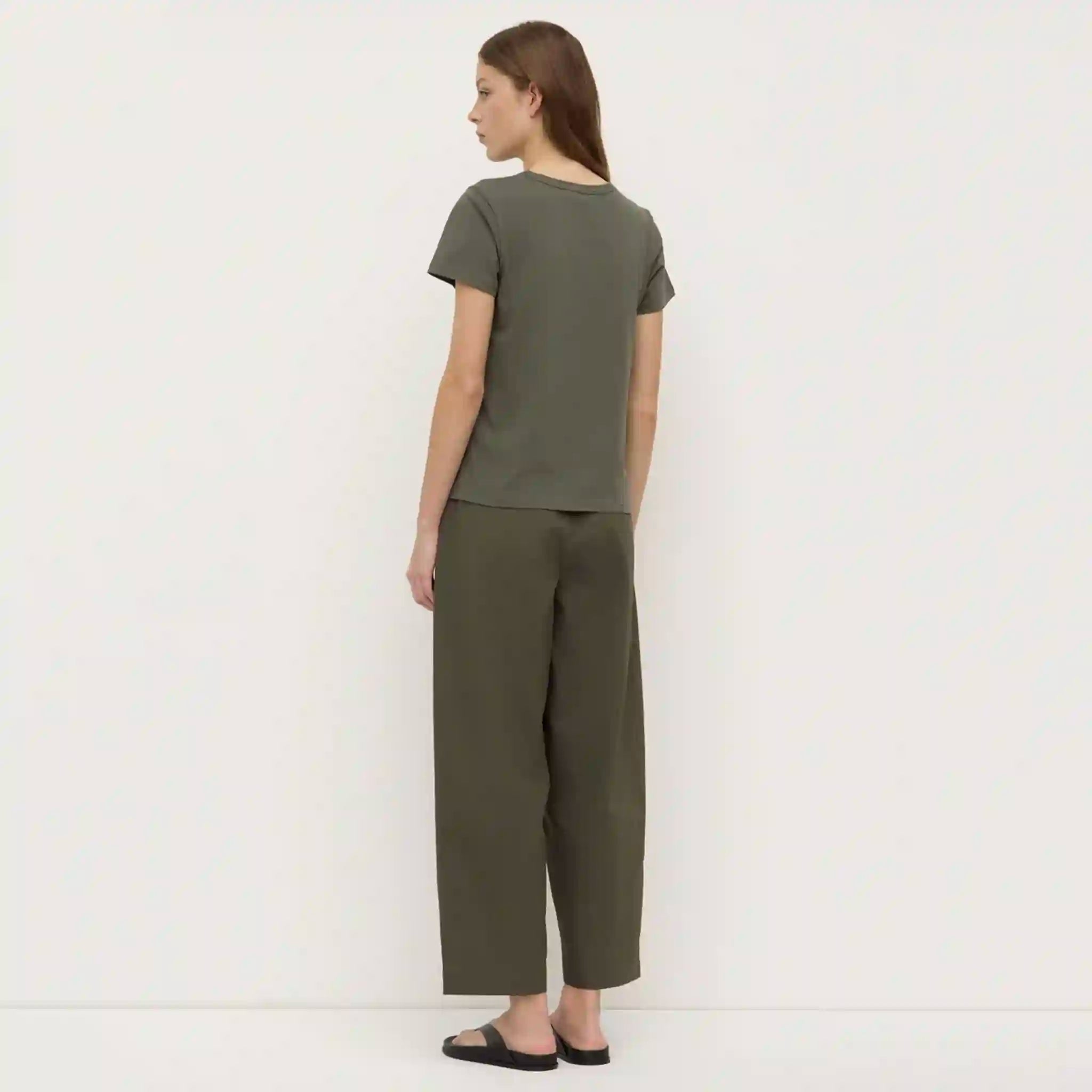 Woman wearing a green t-shirt and pants against a white background