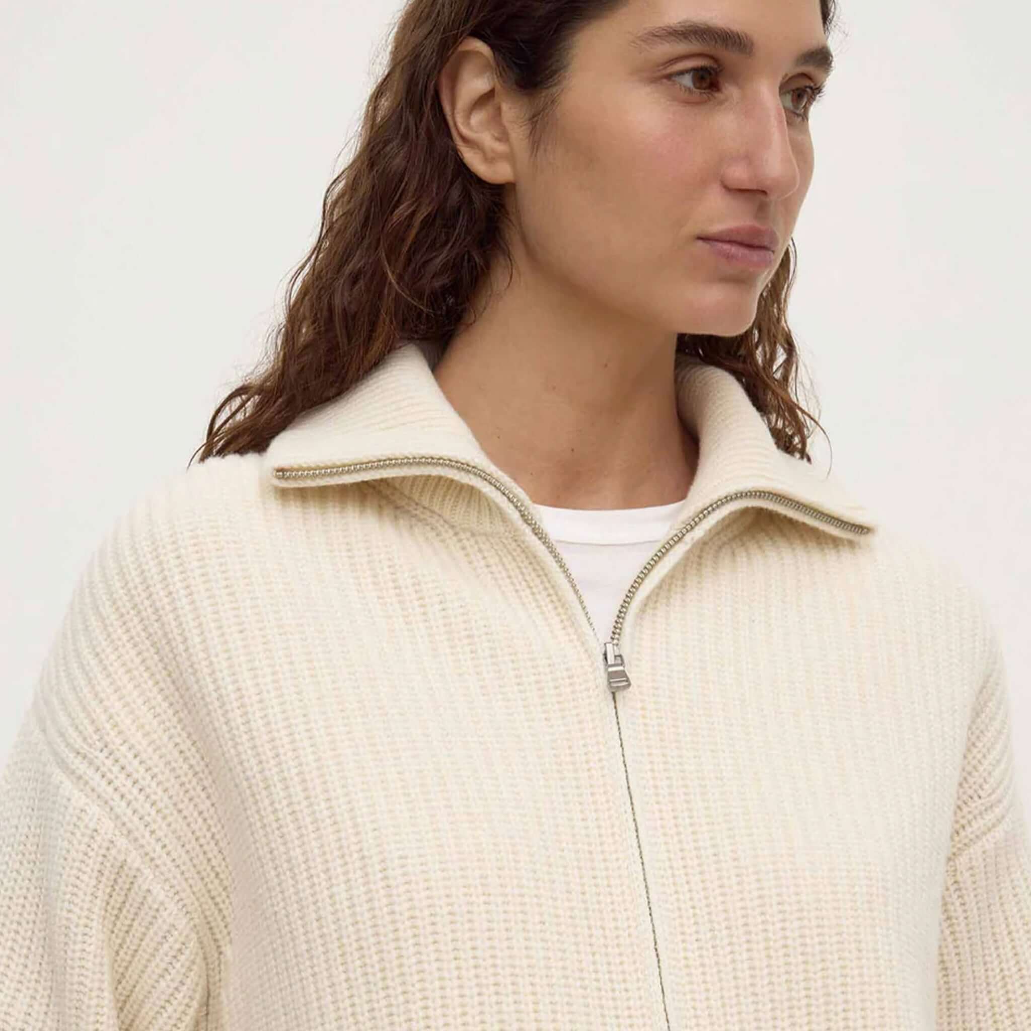 Model wearing Assembly Label Kaia Wool Zip Sweater in Antique White with a funnel neck and full front zip.