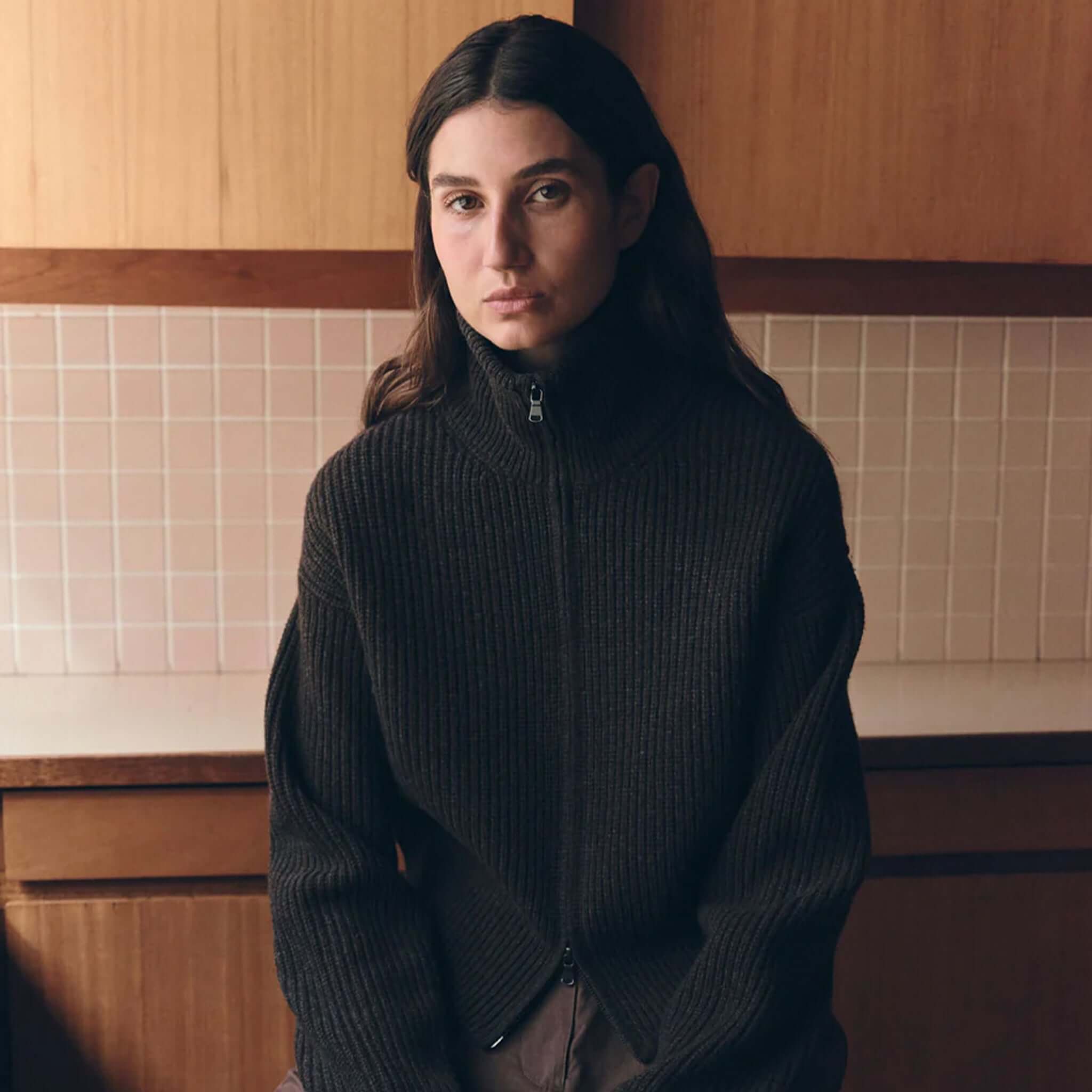 Assembly Label Kaia Wool Zip Sweater - Ganache Marle modeled by a woman in a cozy kitchen setting.
