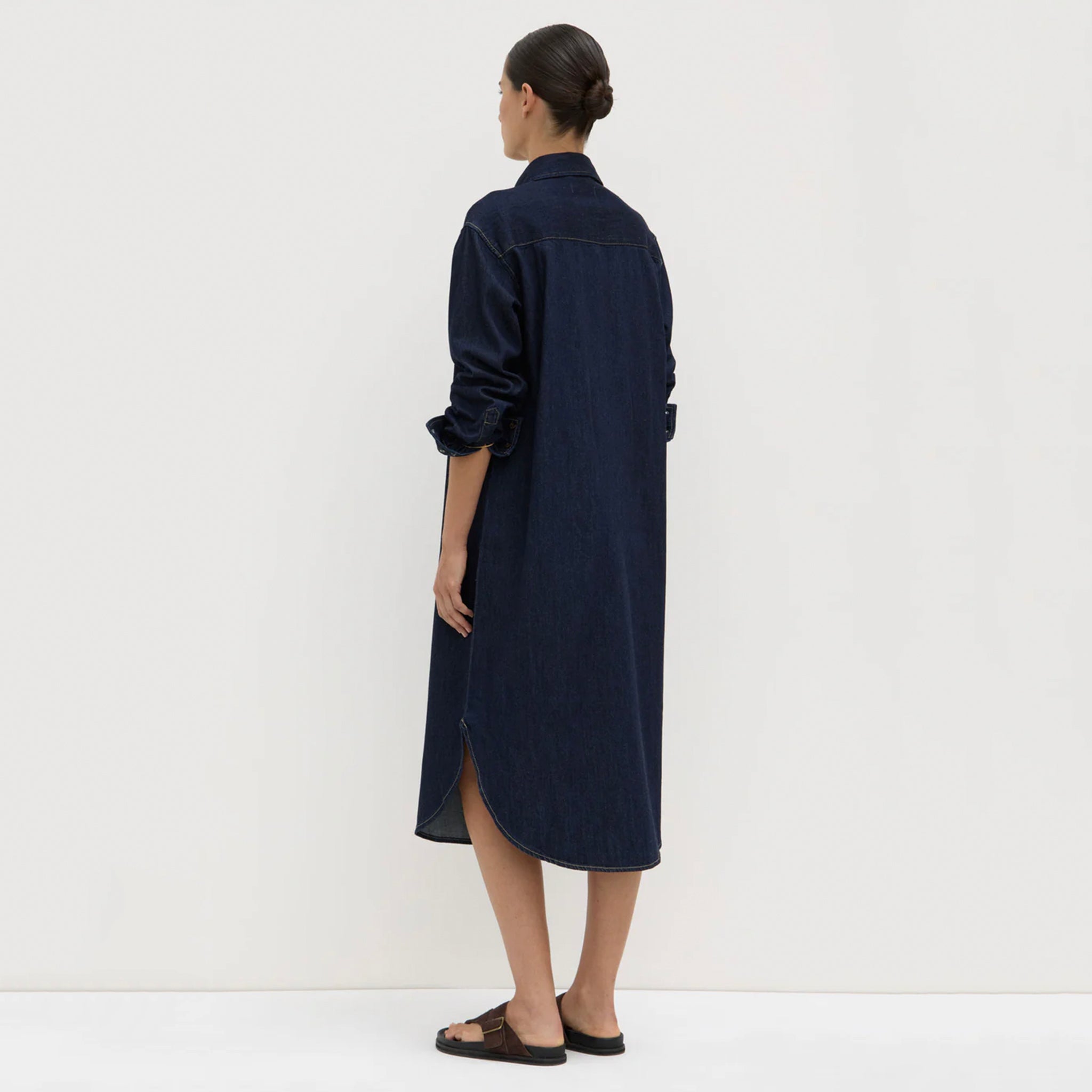 Woman wearing a long navy blue dress against a white background