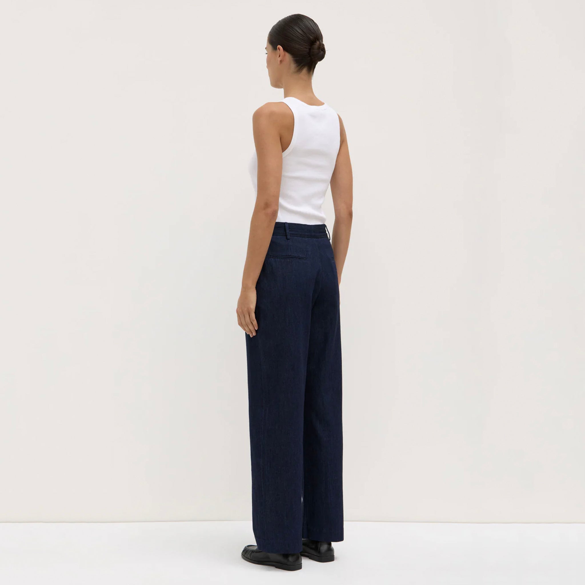 Person wearing navy wide-leg pants and a white top on a white background